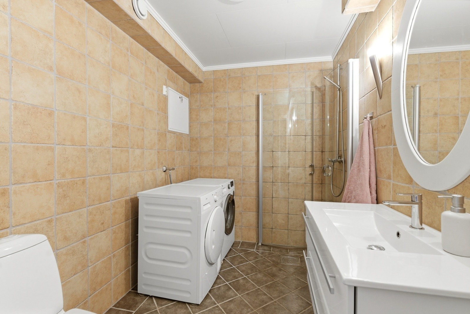 Badet har flisbelagt gulv med varmekabler og en lys baderomsinnredning. Galleribilde