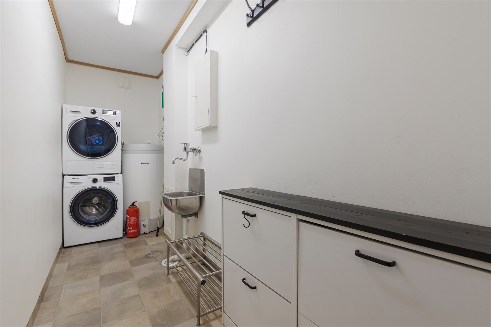 Separat vaskerom i 1. etasje har vinylbelegg med oppkant på gulvet og er utstyrt med skyllekar og opplegg for vaskemaskin og tørketrommel Galleribilde