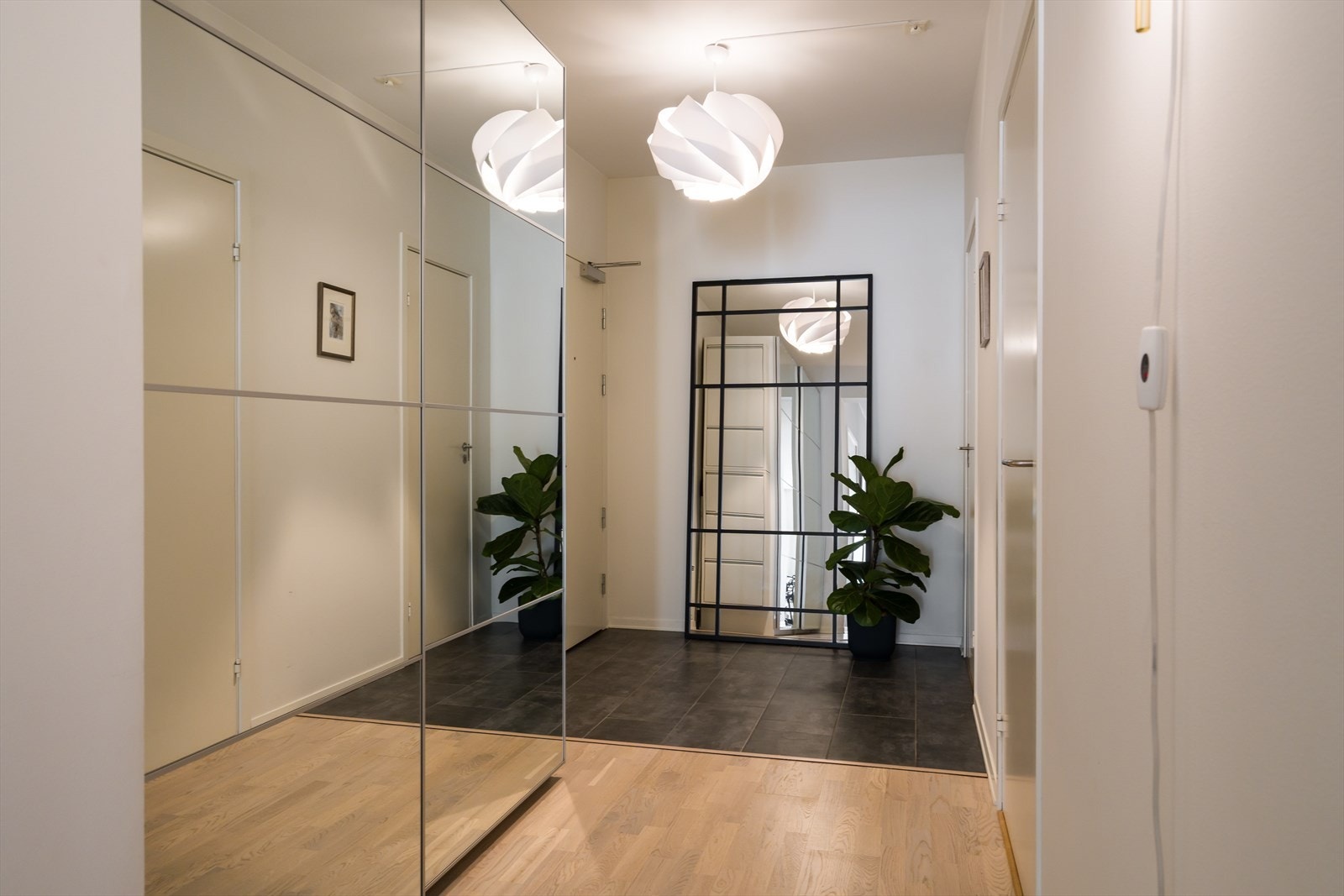 Inngangspartiet har flislagt gulv og en stor skyvedørsgarderobe med speilfronter. Galleribilde