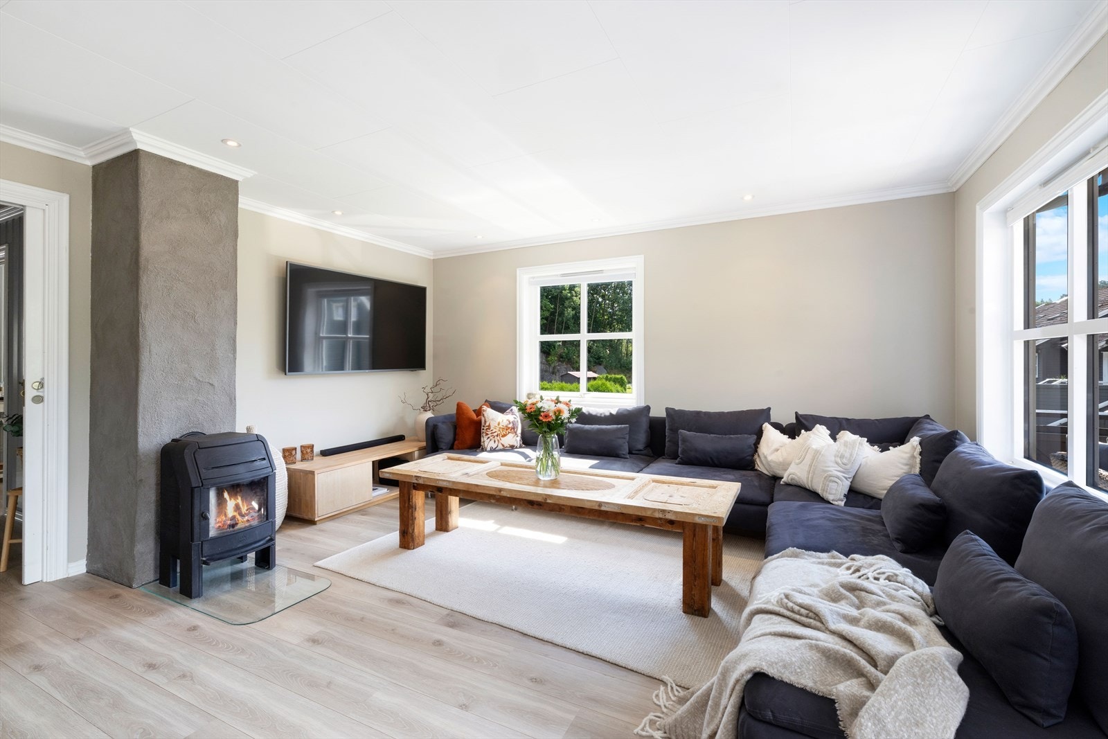 Stue med spotter i tak og laminat på gulv. Vedovn som gir godt med varme. Galleribilde