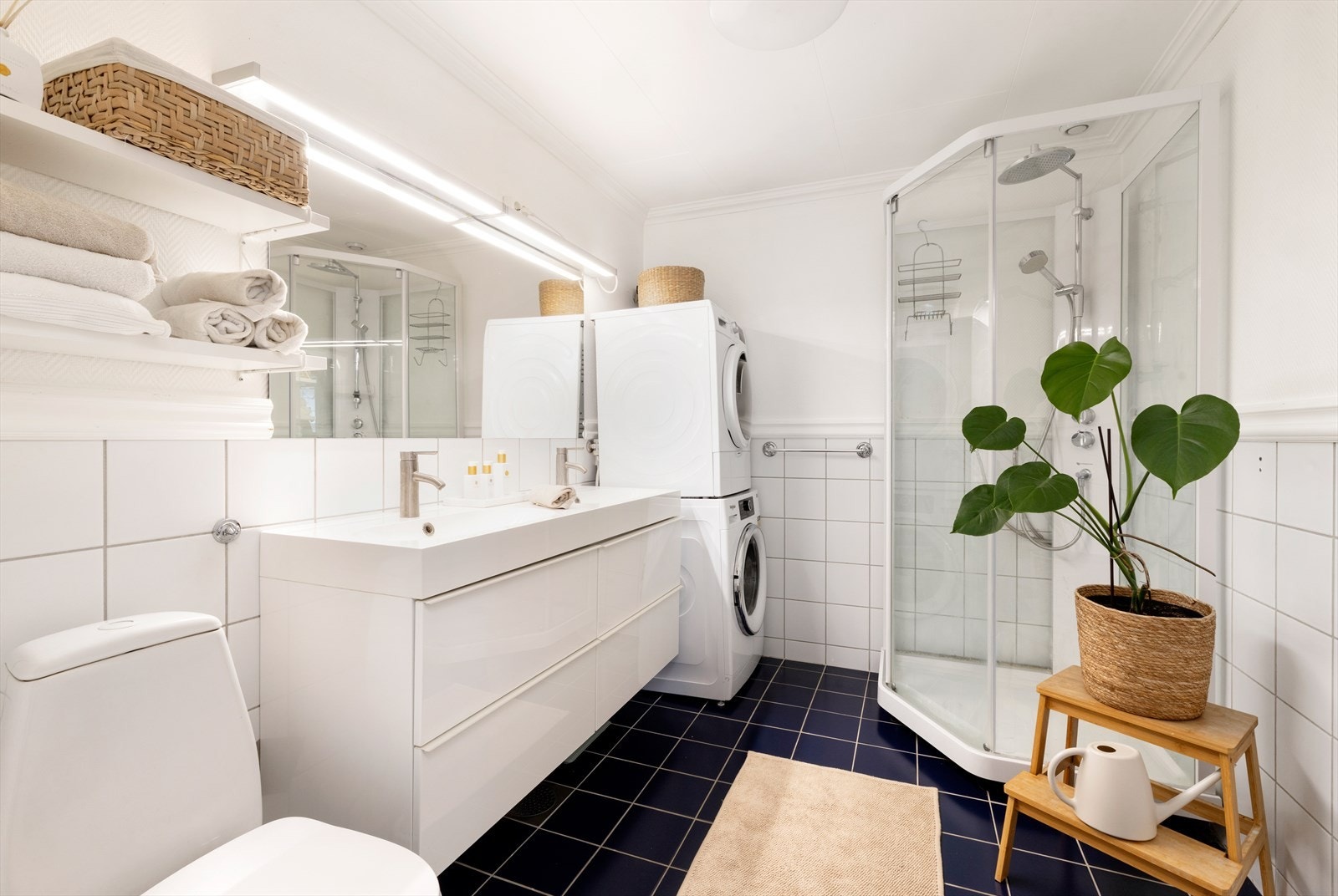 Bad med fliser på gulv. Inneholder dobbeltservant, wc, dusjkabinett og opplegg for vaskemaskin. Galleribilde