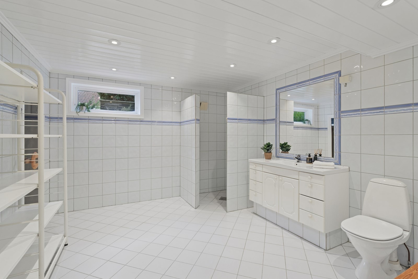 I underetasjen finner man også det tredje baderommet i boligen. Badet er fra 90-tallet og er innredet med lyse fliser på både gulv og vegger. Også her har man varmekabler i gulvet. Galleribilde