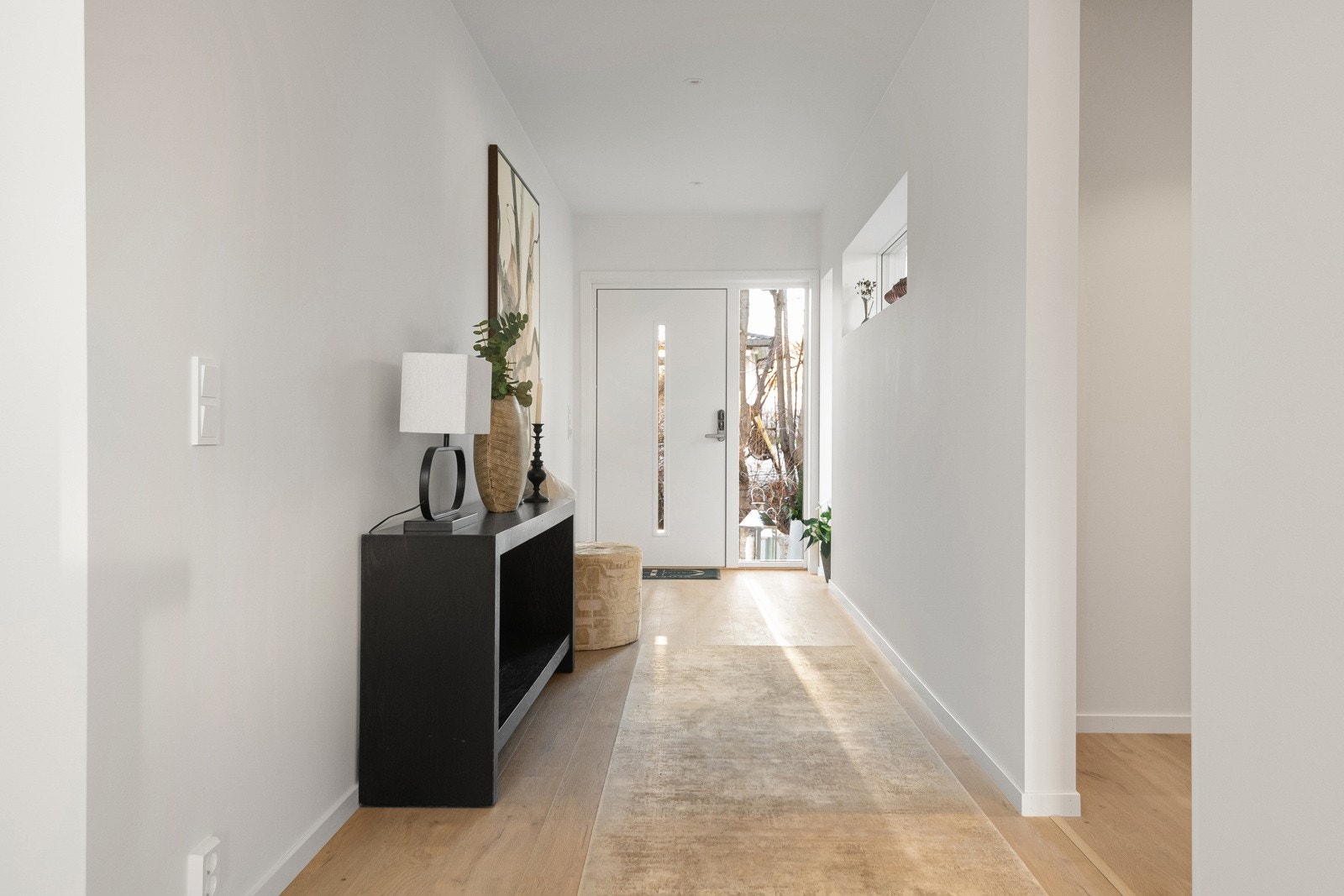 Lys og romslig inngangsparti med god takhøyde og varmekabler i gulvet. Store flater, rene linjer og naturlig lys skaper en rolig og elegant ankomst til boligen. Brann- og lydklassifisert entrédør med kodelås fra Nimly. Galleribilde