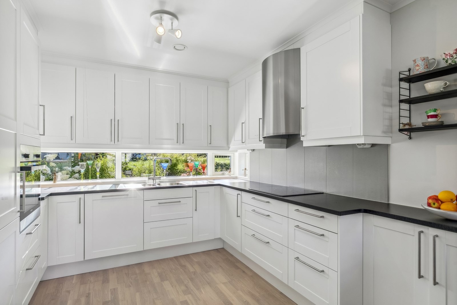 Kjøkkenet er fint plassert i eget hjørne, og er godt utnyttet med skap-, skuffer og benkeplass. Galleribilde