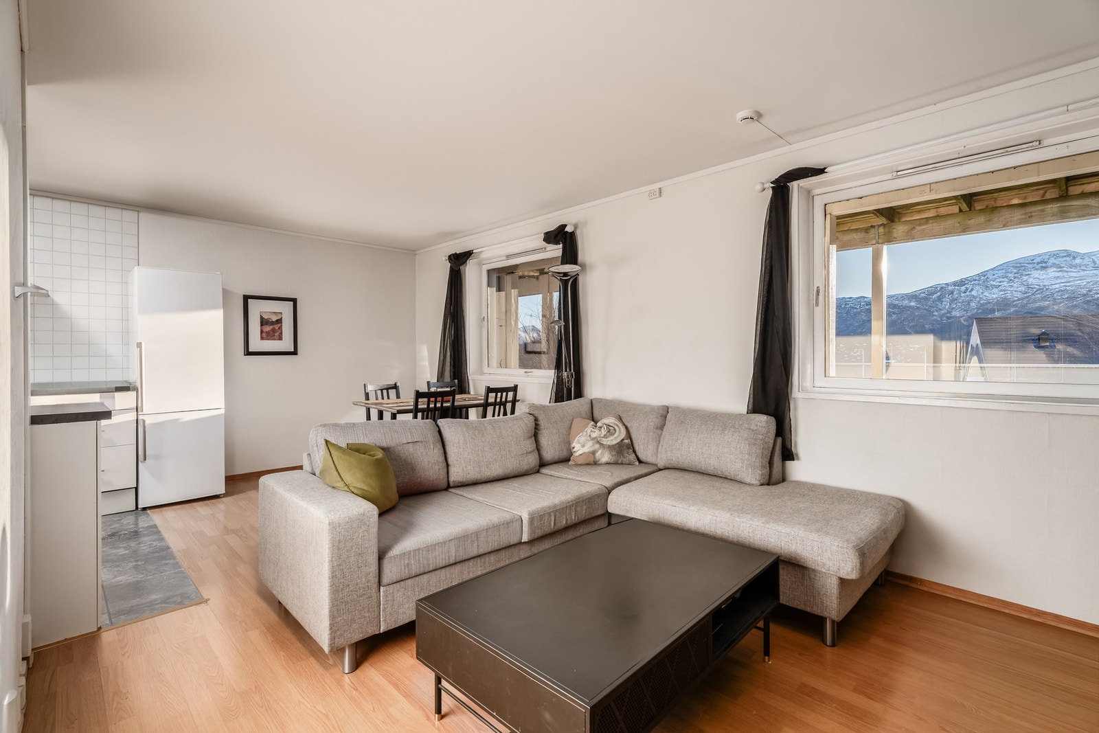 Stue og kjøkken i åpen løsning i underetasjen. Selv i sokkeletasjen har man utsikt mot fjord og fjell. Galleribilde