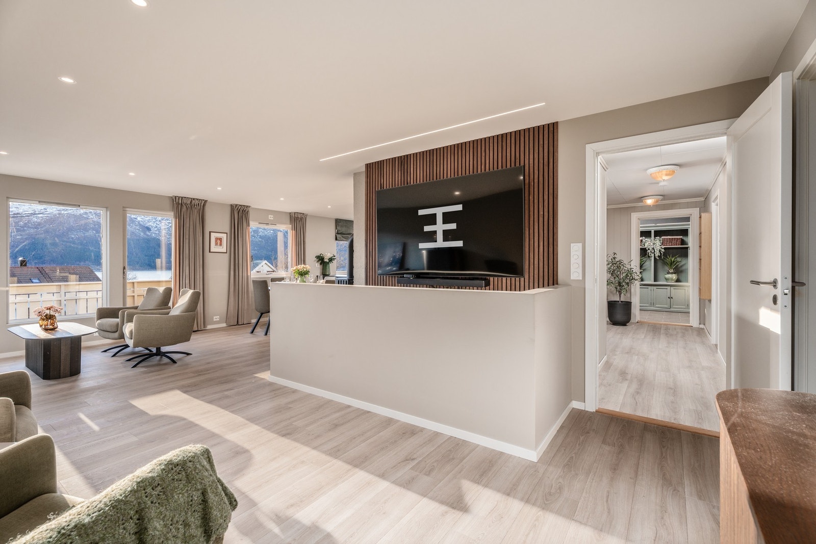 Elegant spilevegg med vegghengt TV. Stua har dessuten plass til flere naturlige soner for møblering. Legg også merke til ledspotter i himling. Galleribilde