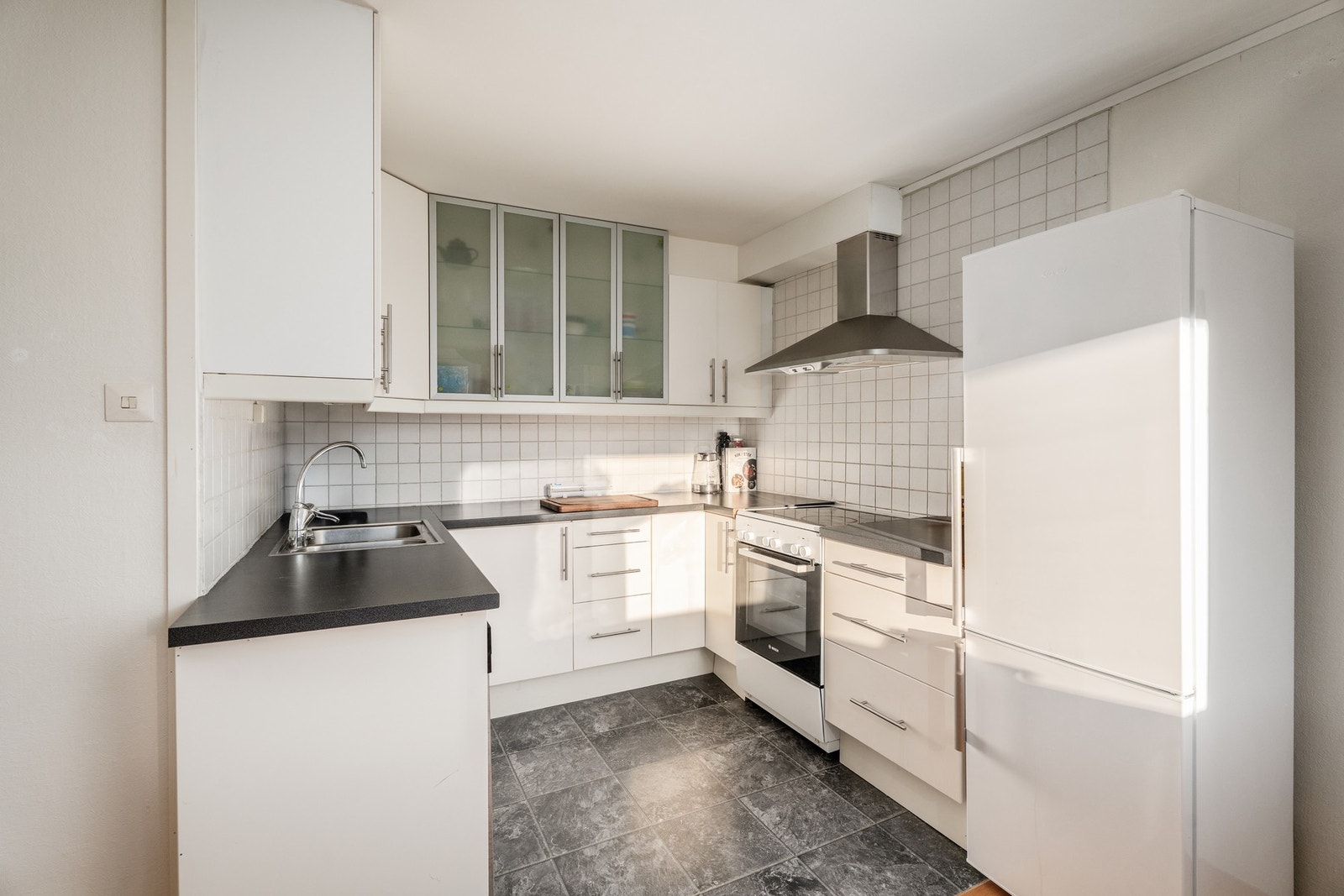 Kjøkkenet i underetasjen har innredning fra IKEA og klassiske, hvite fliser på vegg mellom overskap og underskap. Galleribilde