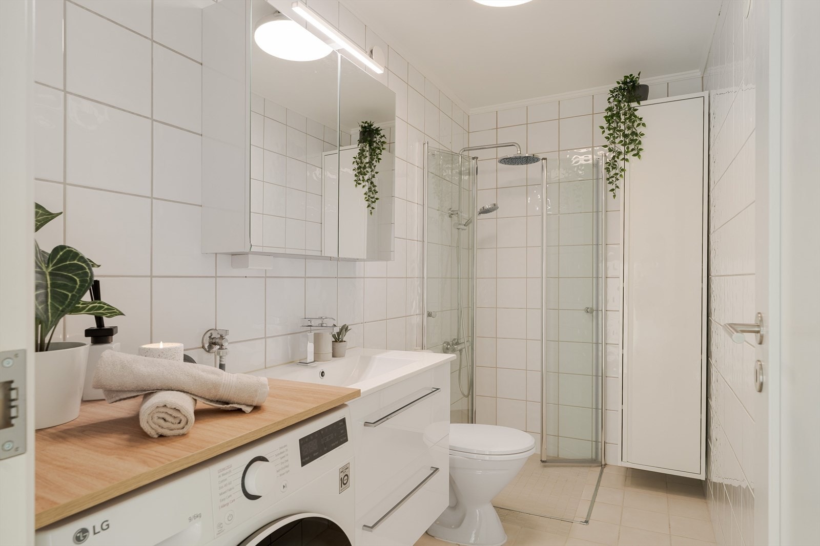 Badet er på ca. 4m², her er det flis på gulv og vegger. Malt betong i himling. Utstyrt med innfellbare dusjdører, naturlig avtrekk, opplegg for vaskemaskin, servantskap og wc. Galleribilde