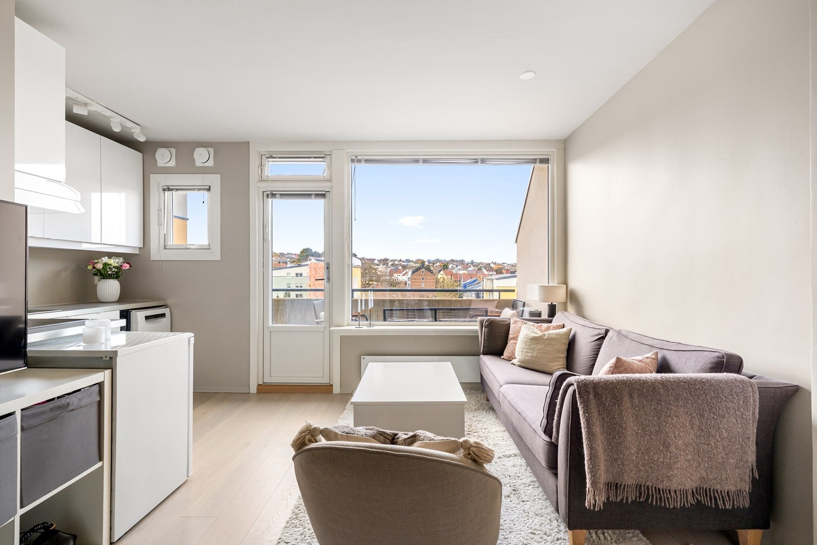 Lys stue med åpen løsning mot kjøkken og direkte utgang til balkongen. Galleribilde