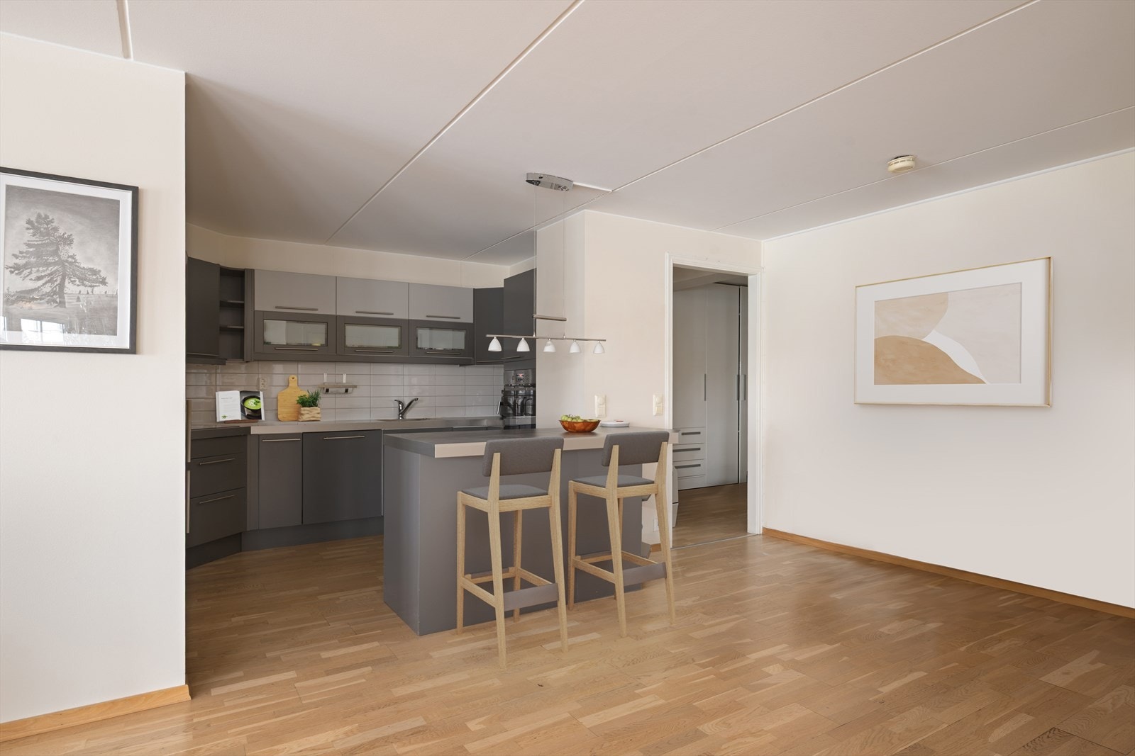 Lys og trivelig åpen stue/kjøkkenløsning med gode arbeidsflater og kjøkkenøy med sitteplasser. Gjennomgående 3-stavs eikeparkett gir et helhetlig og tidløst uttrykk. (Digitalt møblert bilde) Galleribilde