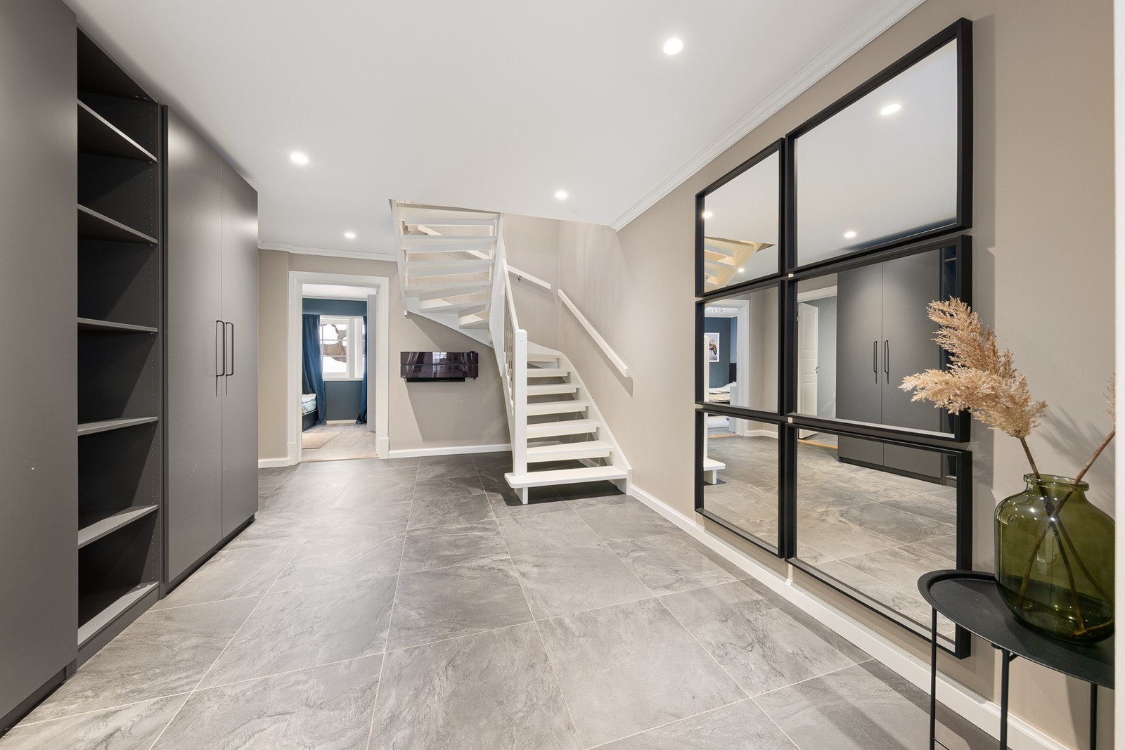 Gulvet er flislagt og overflater malt i lyse toner. En romslig garderobeløsning gir rikelig med plass til oppbevaring av yttertøy og sko. Galleribilde