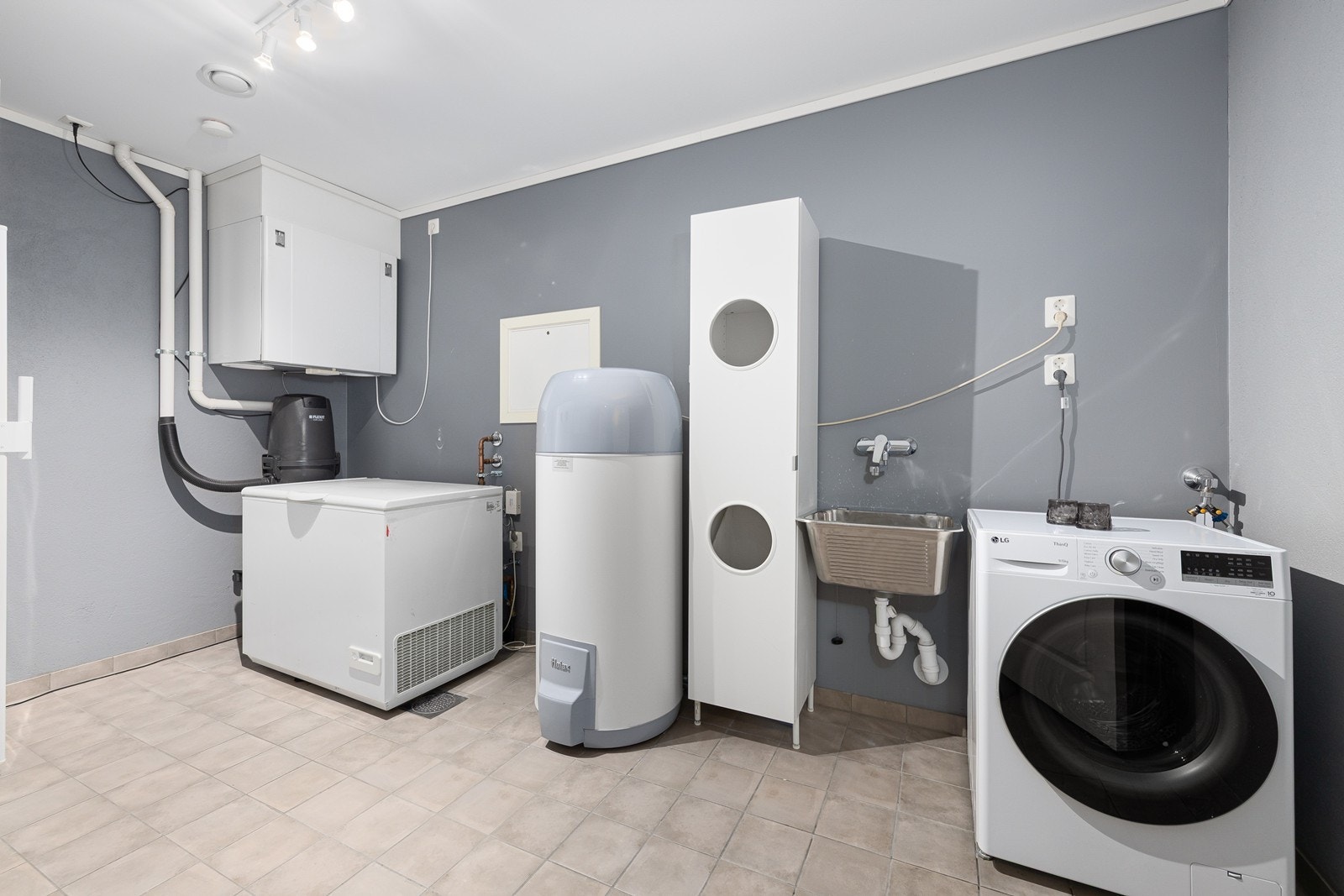 Det tekniske rommet er utstyrt med vaskekum i stål og opplegg for vaskemaskin, og gir gode arbeidsforhold for husets tekniske behov. Galleribilde