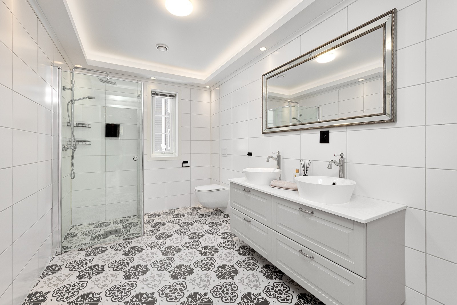 Det stilrene og sjarmerende badet har flislagte gulv og vegger, samt behagelig gulvvarme som gir ekstra komfort. Galleribilde