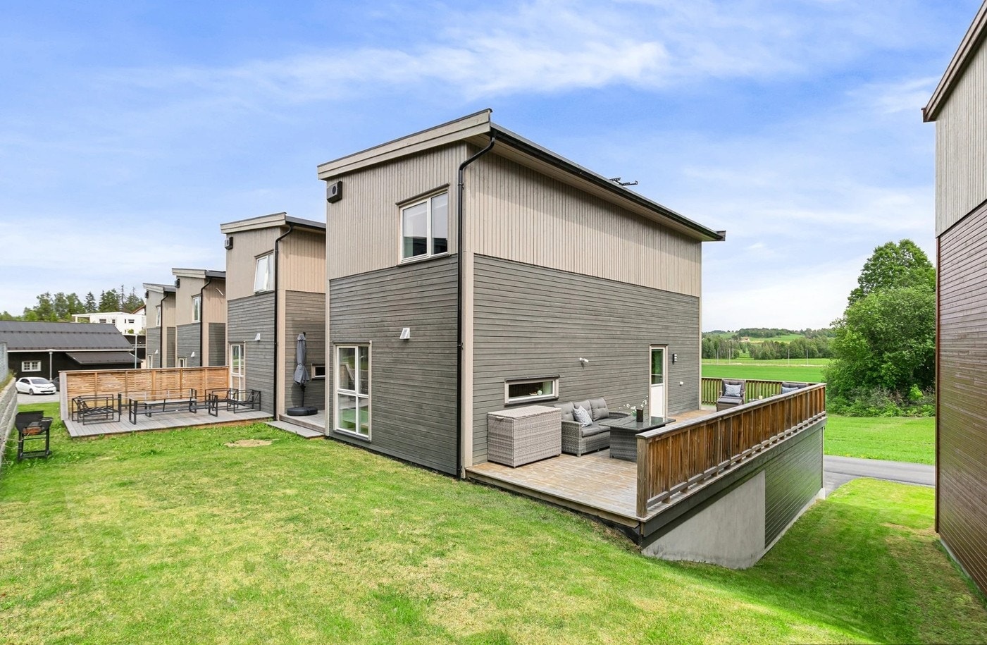 Hage med plen som strekker seg ned bakken til framsiden av bygget. Galleribilde