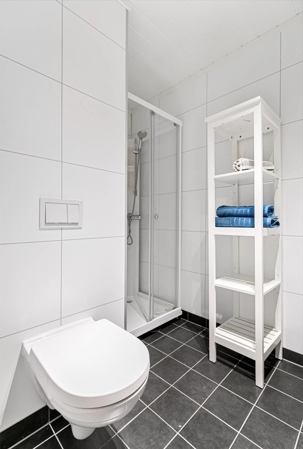 Dusjkabinett i hjørnet på badet og vegghengt toalett. Galleribilde