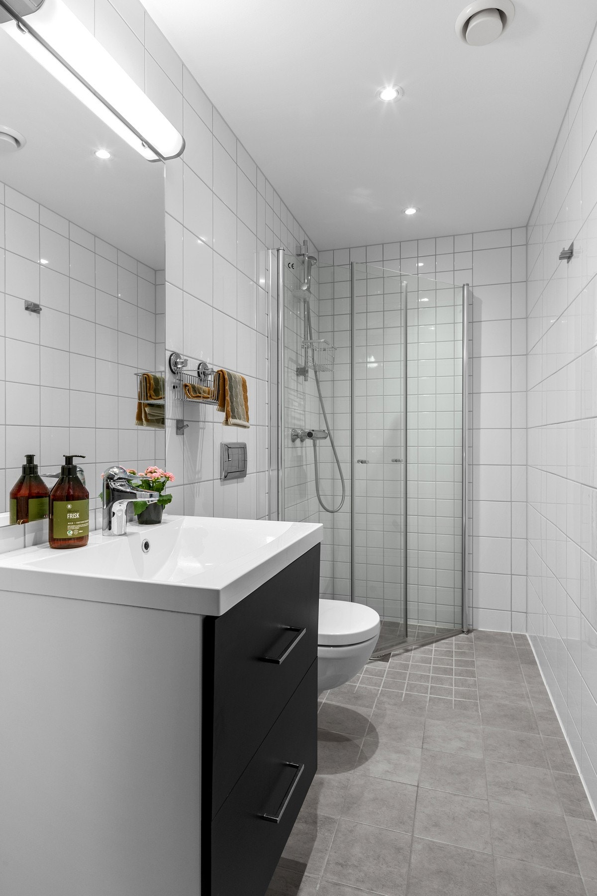 Bade/gjestebad er innredet med servant på skuffeseksjon og speil. Videre er rommet utstyrt med vegghengt toalett og innfellbare dusjvegger. Galleribilde