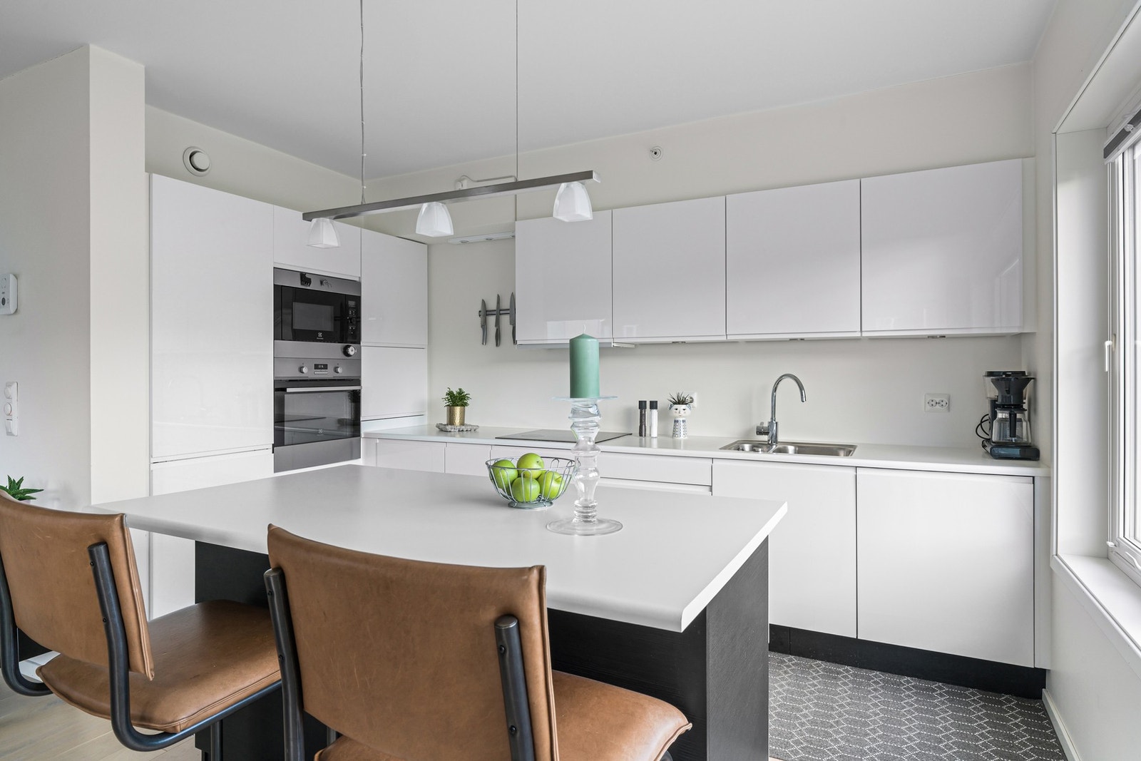 En praktisk kjøkkenøy gir ekstra arbeidsflate og har sitteplass for barstoler - perfekt for en rask frokost eller hyggelig selskap mens maten tilberedes. Galleribilde