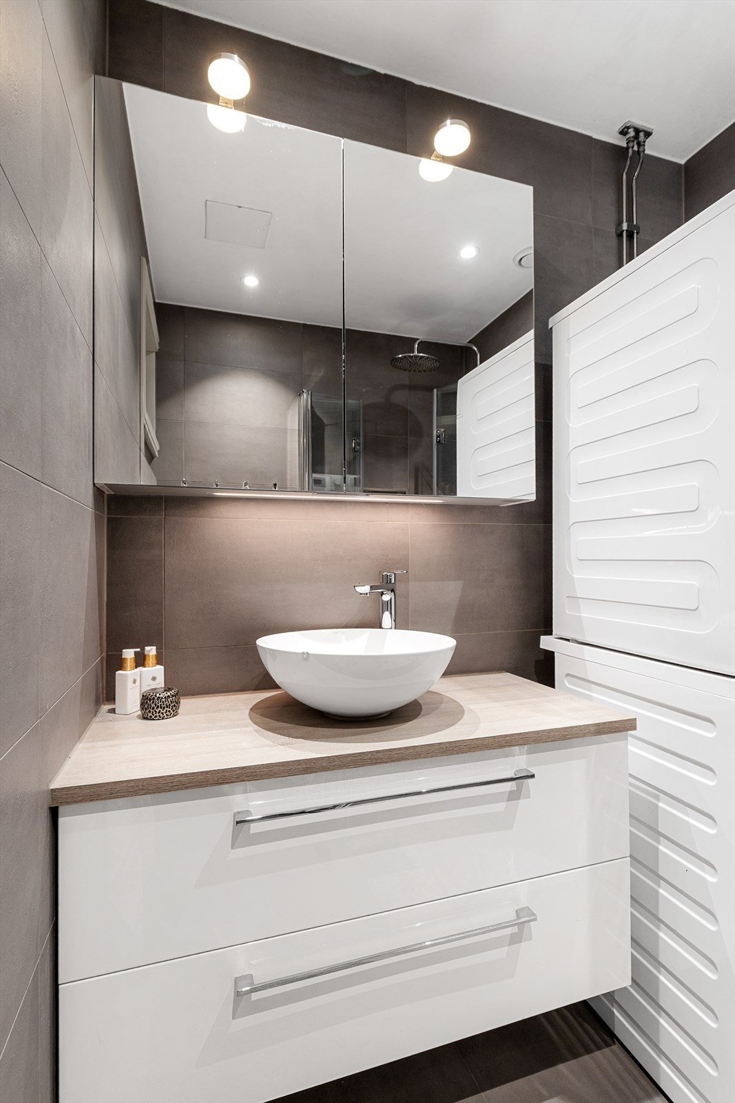 Badet er innredet med servant på innredning og dusjhjørne med svingbare glassdører. Galleribilde