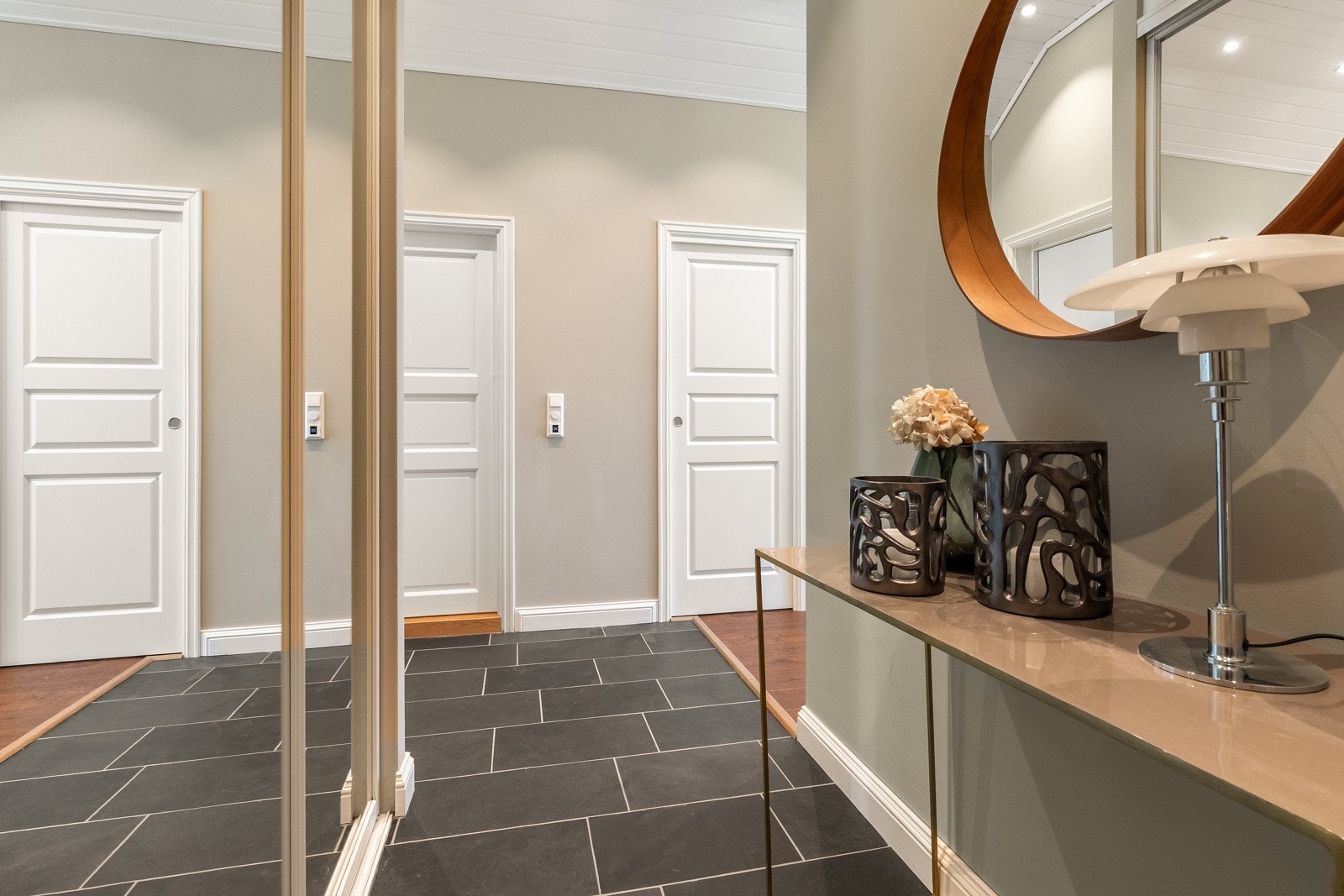 Romslig og praktisk entré/gang med stor skyvedørsgarderobe med speilfronter og flislagt gulv med termostatstyrte varmekabler. Galleribilde