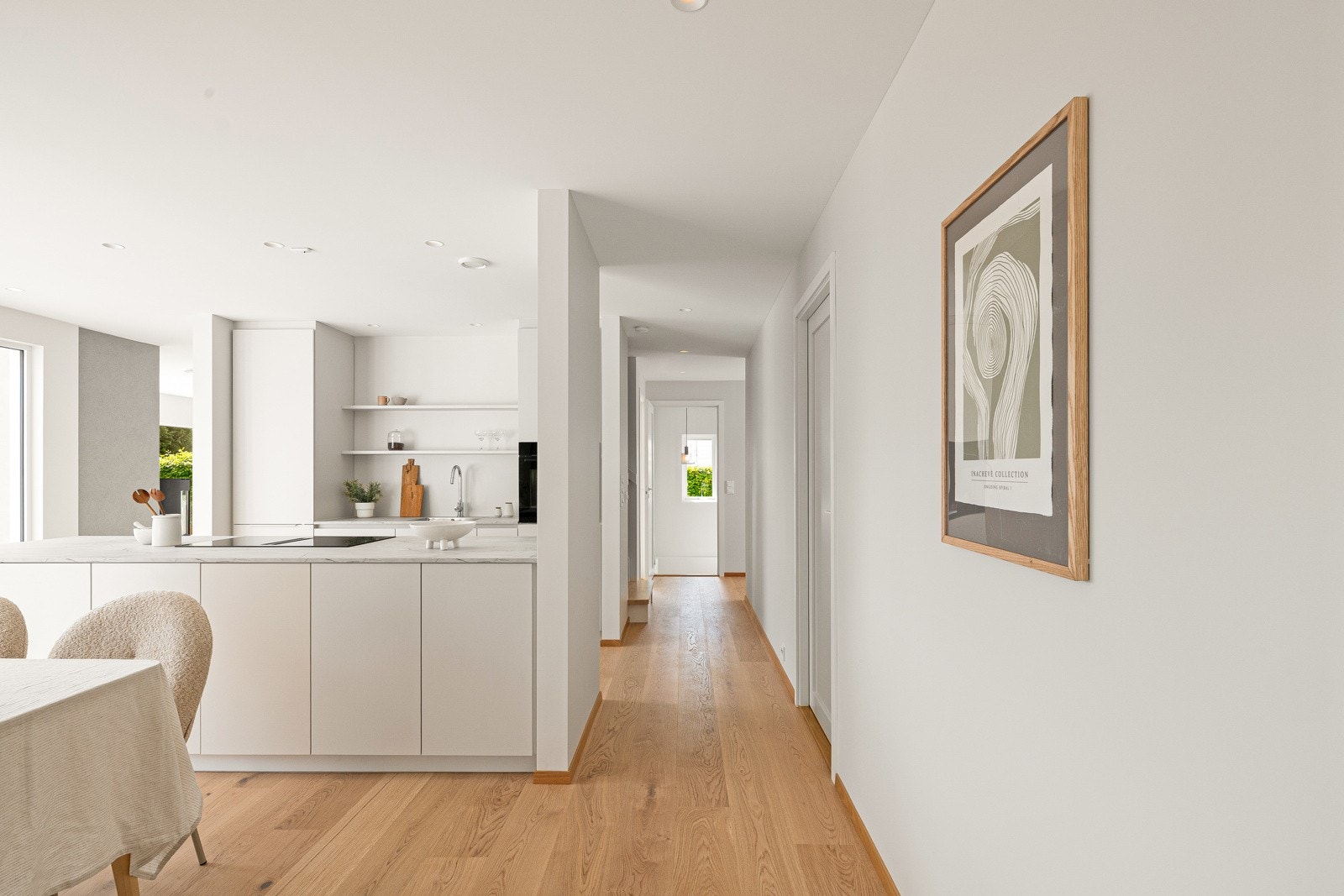 Kjøkkenet er moderne og stilfullt, med hvite, glatte fronter og lys laminatbenkeplate i marmor-look med nedfelt kum. Galleribilde