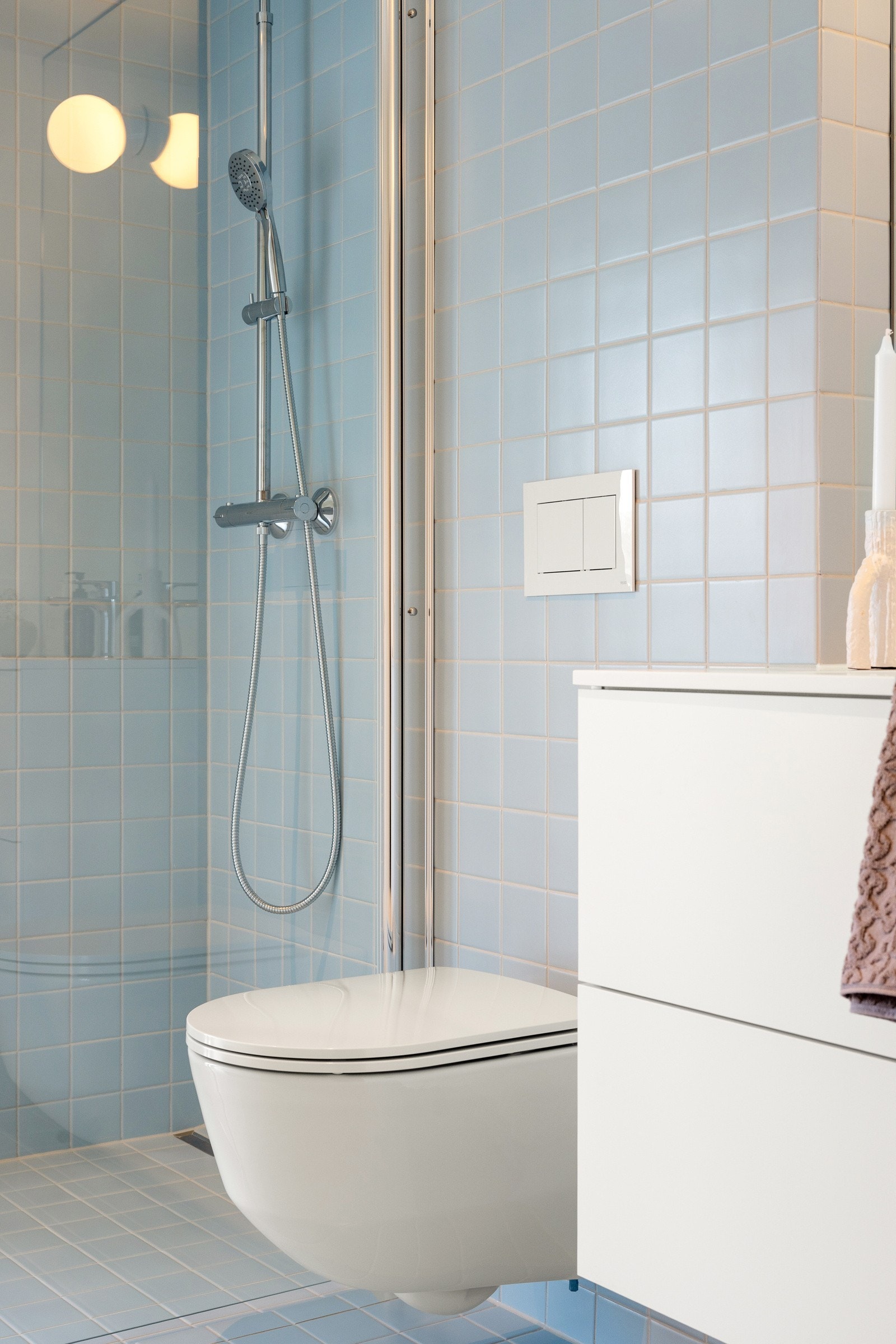 Baderomsinnredningen har hvite fronter og består av en heldekkende servant på en skuffseksjon, og over er det et stort speil med moderne belysning. Galleribilde