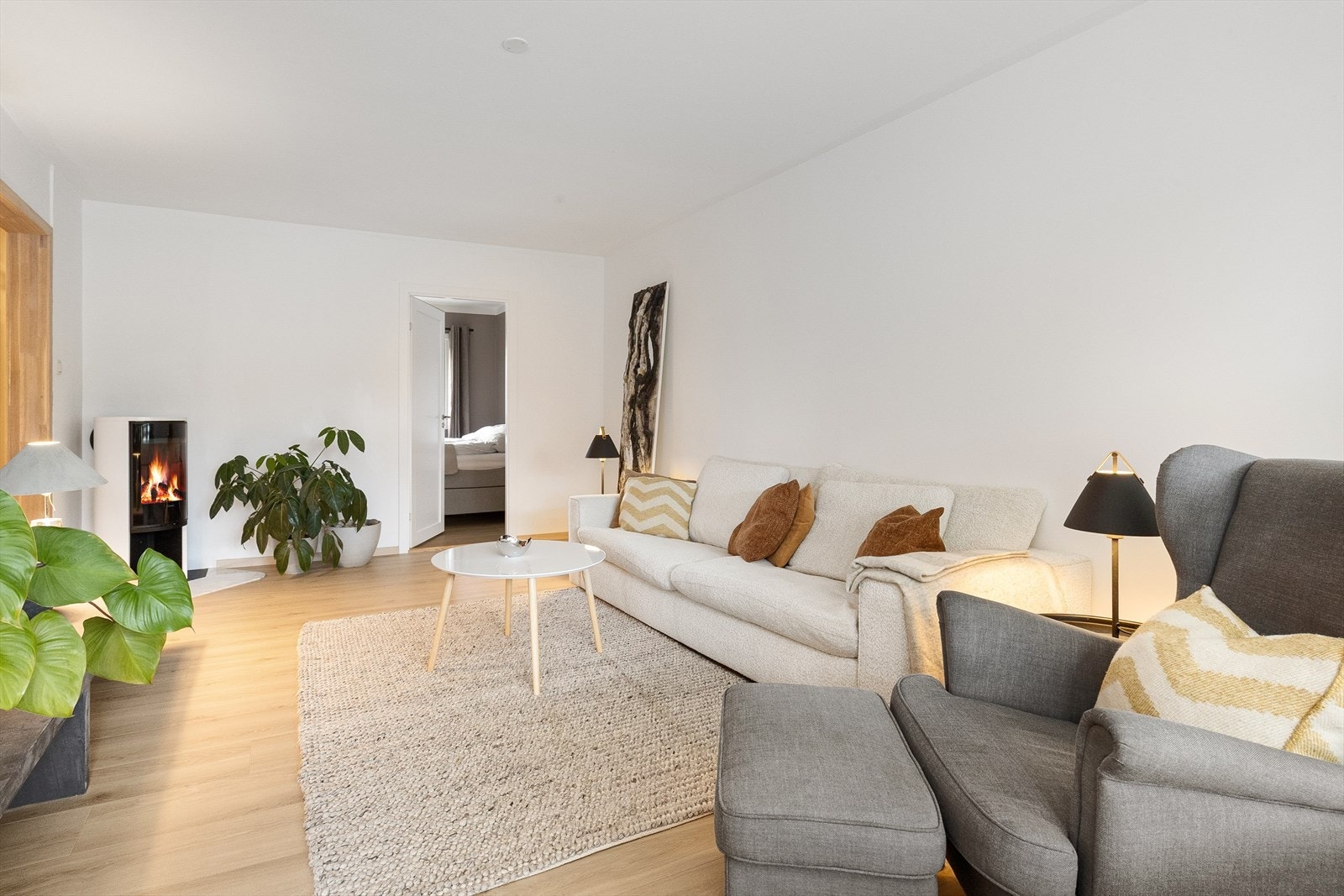 Slette malte tak, veggflater med enstavs laminat på gulv. Contura peisovn fra 2023 i stuen Galleribilde