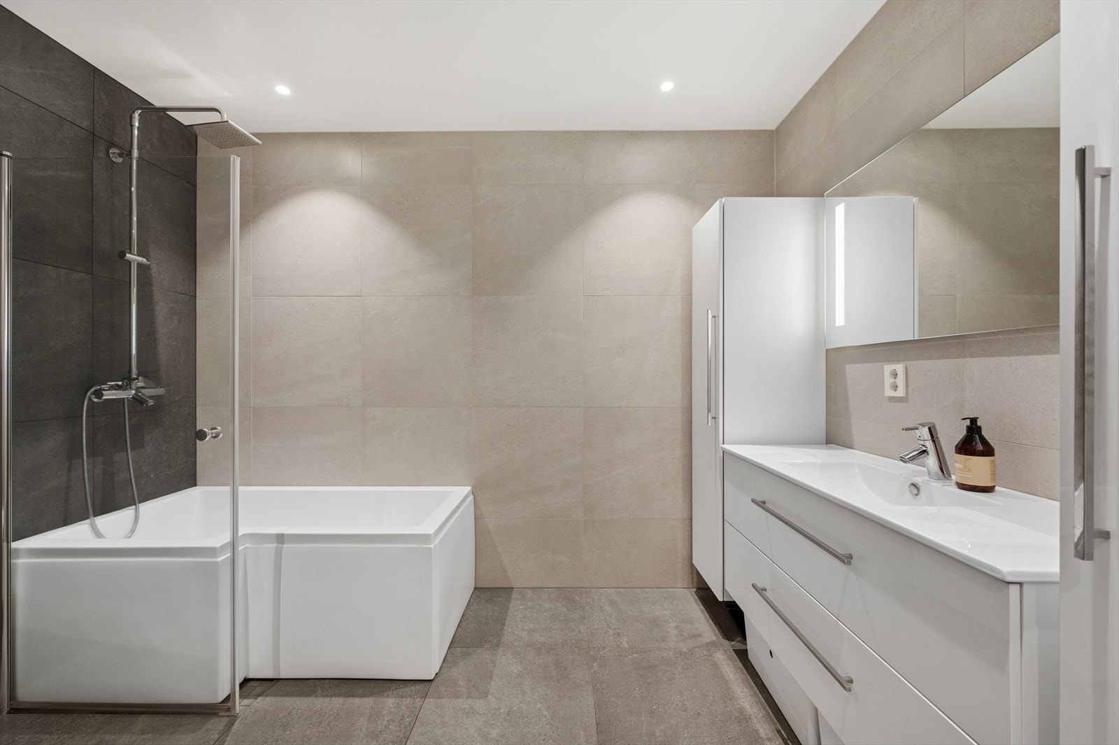 Baderomsinnredning med hvite fronter, servant, speil og belysning. Galleribilde