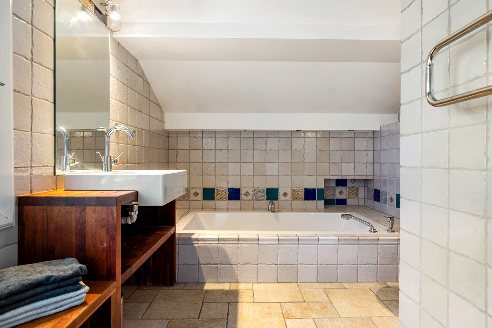 Badet i 2. etasje har flislagte overflater og er innredet med innmurt badekar, dusjhjørne, vegghengt toalett og servant på stilfull innredning i tre. Galleribilde