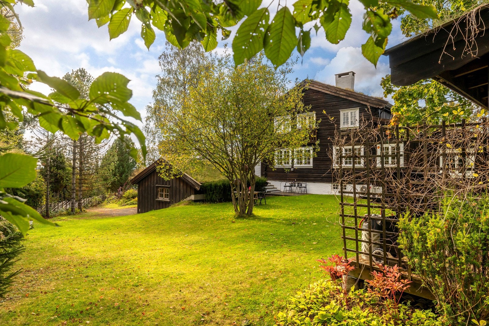 Hagen er frodig og velstelt, med store gressflater, busker og trær som skaper en skjermet og fredelig ramme rundt eiendommen. Galleribilde