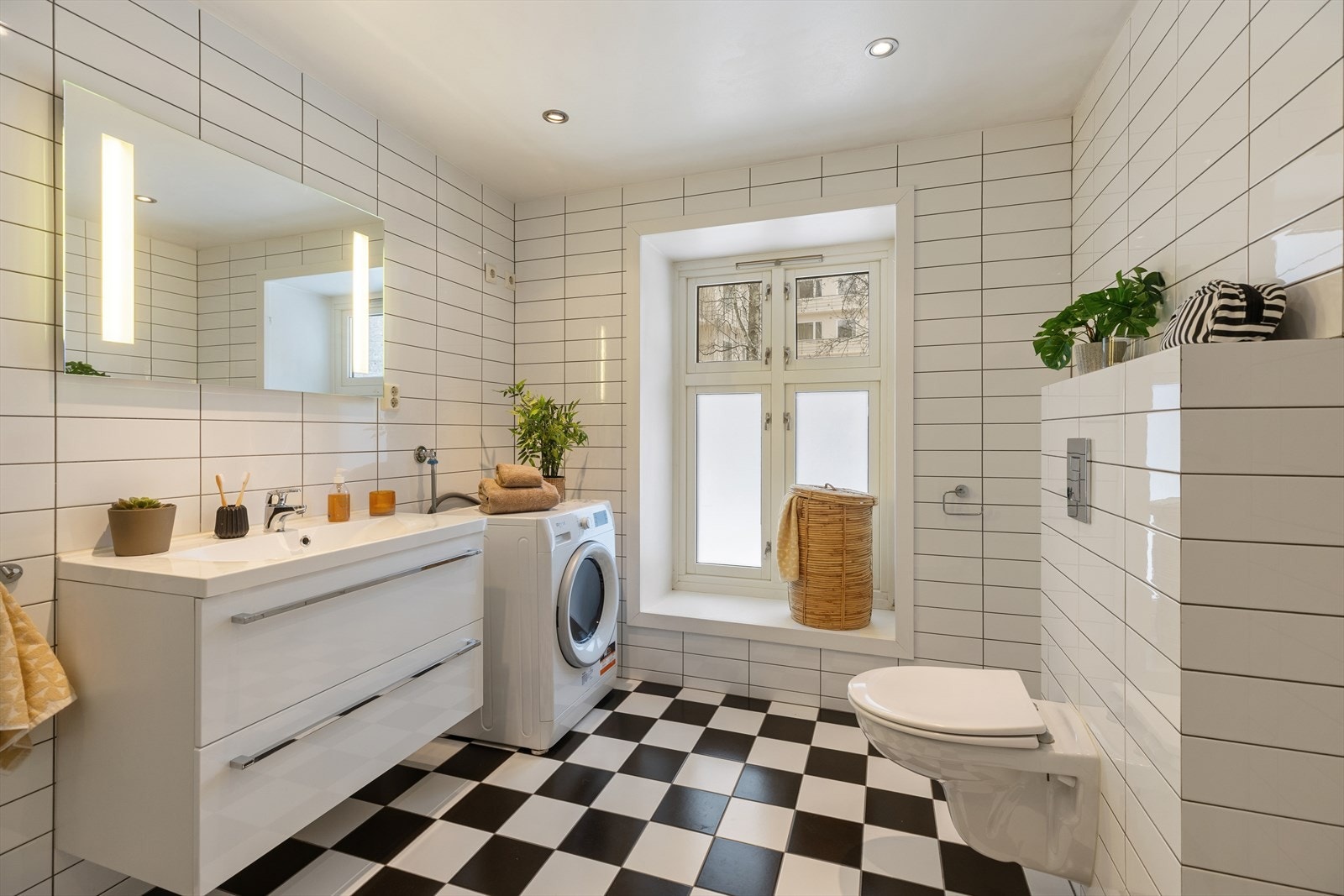 Stort flislagt baderom med opplegg for vaskemaskin. Galleribilde