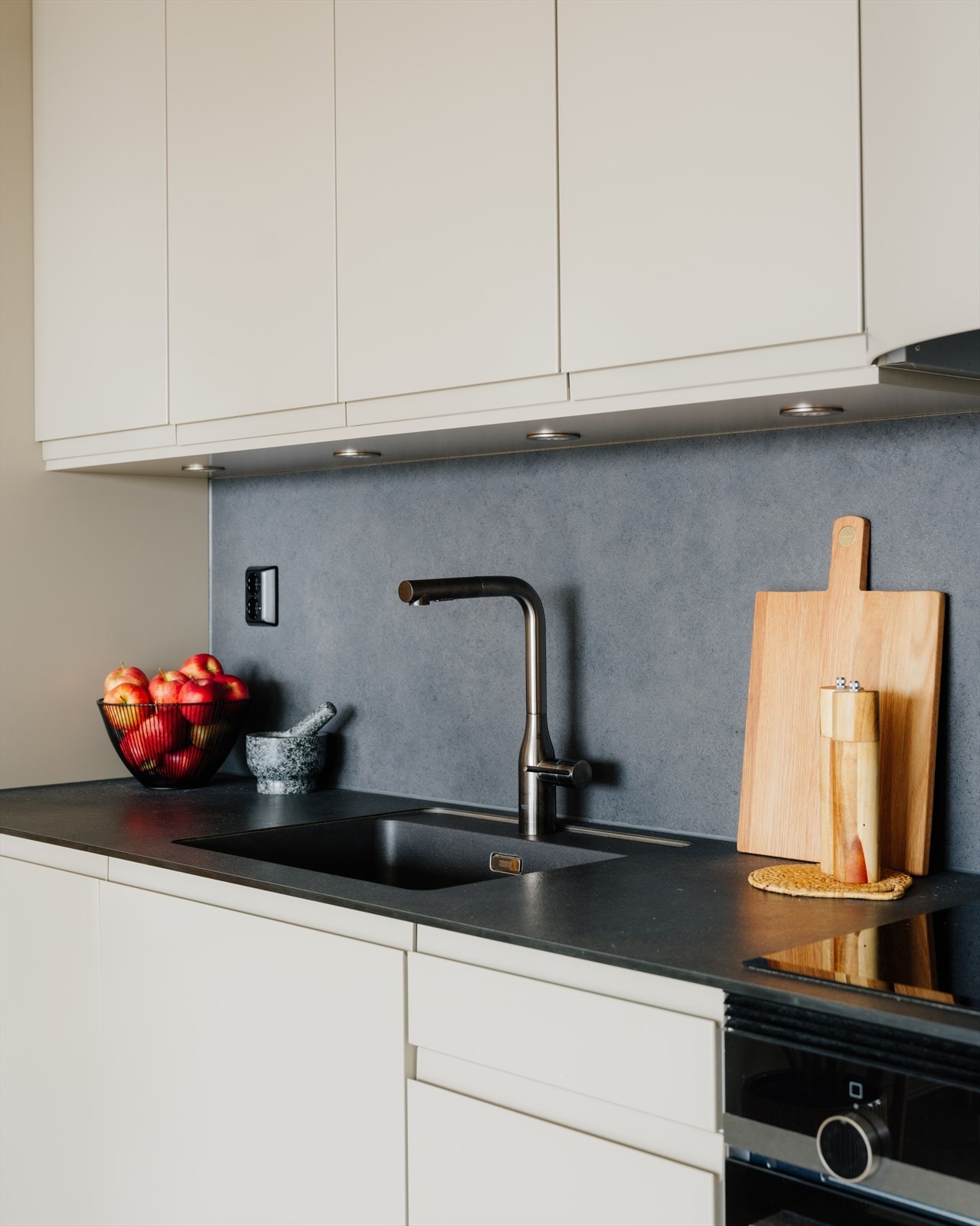 Nedfelt oppvaskkum, kjøkkenarmatur med uttrekk og induksjonstopp. Det er også kompaktlaminat mellom overskap og benkeplate Galleribilde