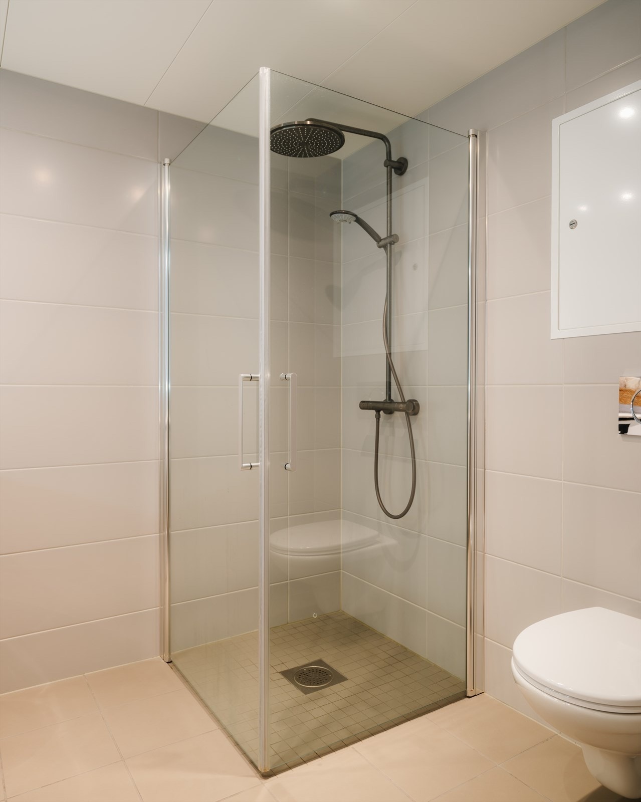 Badet har et moderne og tidløst uttrykk, og er innredet med vegghengt toalett og dusjhjørne med regnfallsdusj Galleribilde