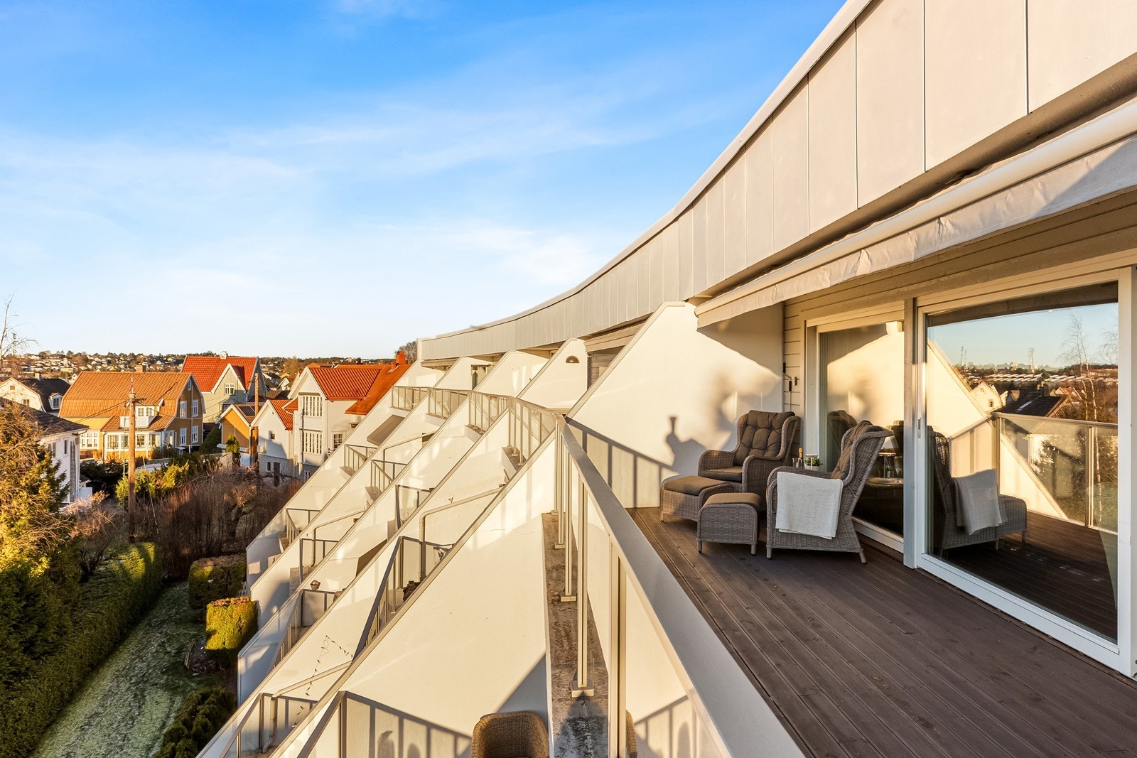 Vestvendt balkong med tregulv gir utsikt over nabolaget og solnedgangen. Galleribilde