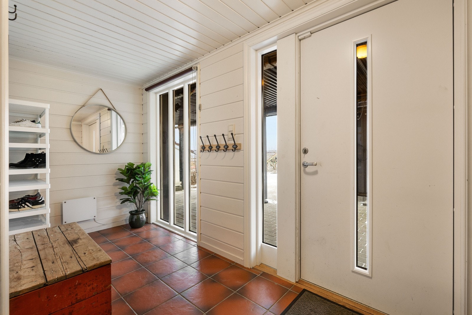 Romslig vindfang med fliser på gulv, panel på vegger og i himling Galleribilde