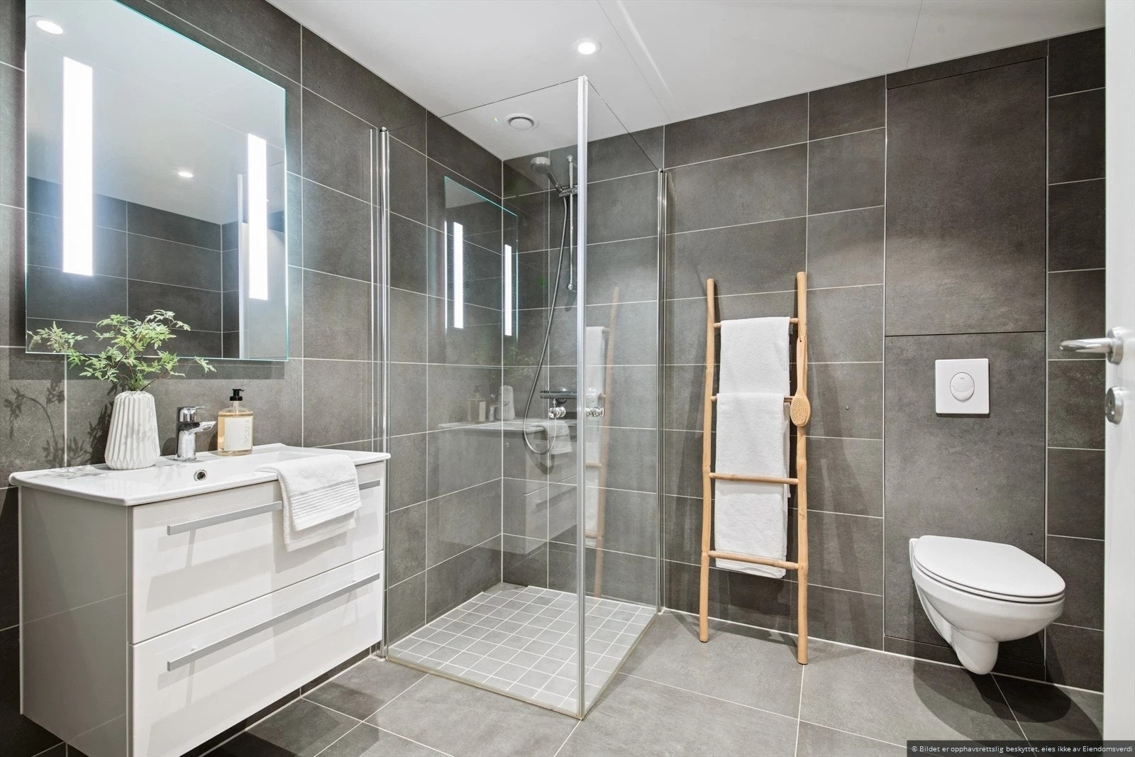 Flislagt bad med servant, dusjhjørne, toalett og vaskemaskin. Galleribilde