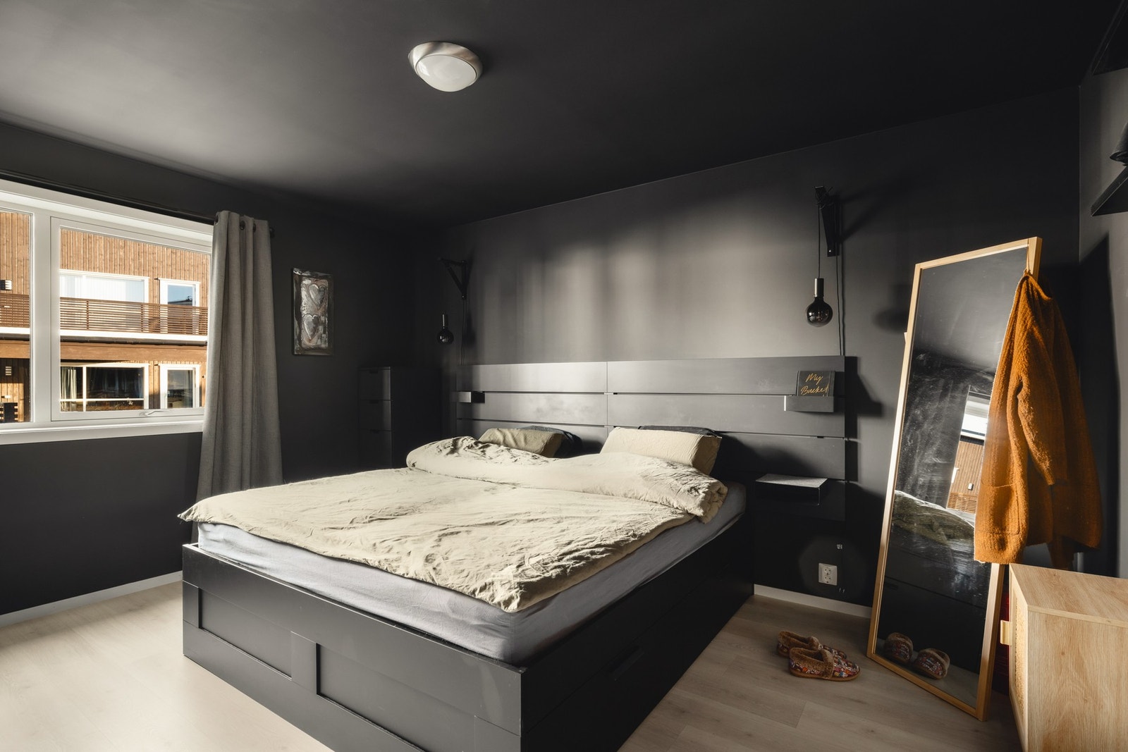 Soverommet har mørke vegger og tak, med et stort vindu som gir naturlig lysinnslipp. Galleribilde