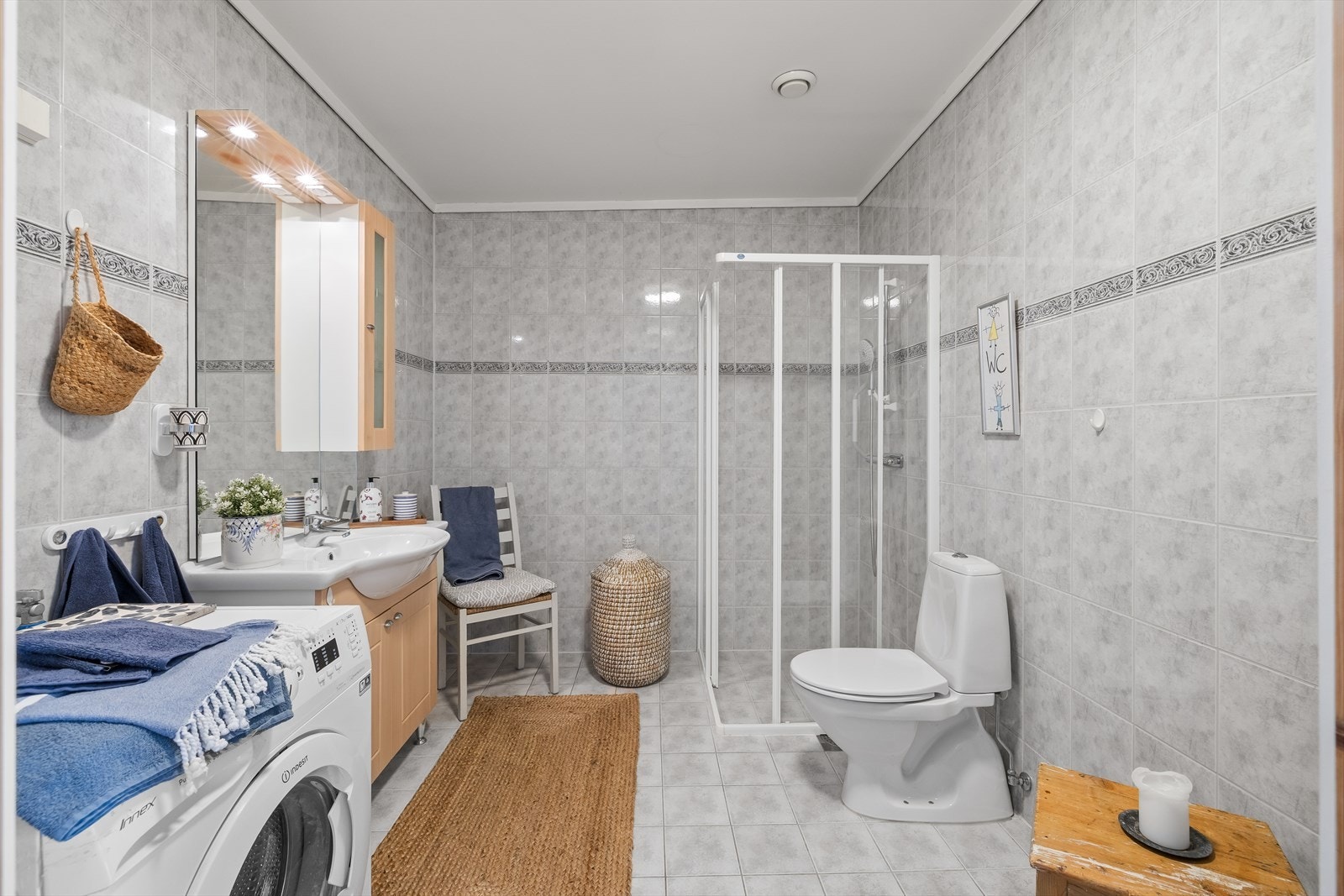 Det er stort fislagt bad med fliser på gulv og vegger. Badet er utstyrt med innredning med nedfelt servant, toalett, dusjvegger/hjørne og opplegg for vaskemaskin. Galleribilde