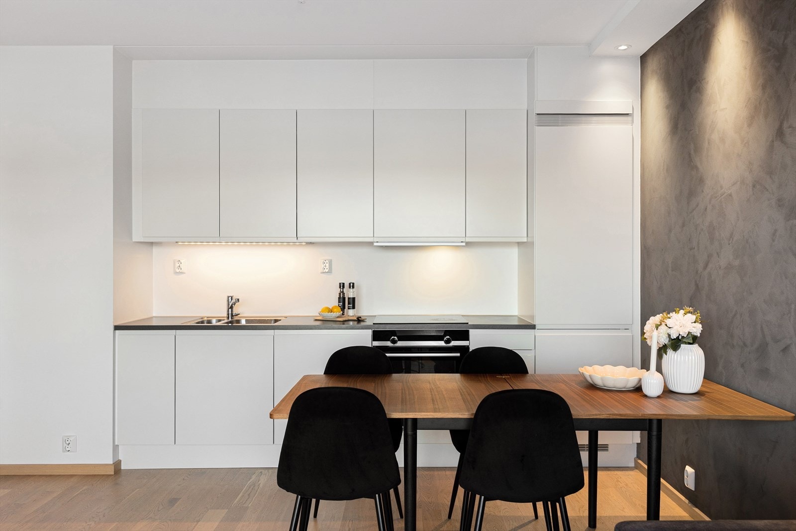 Kjøkkeninnredningen har hvite, glatte fronter og laminat benkeplate med nedfelt oppvaskkum og ettgreps, svingbart blandebatteri. Galleribilde