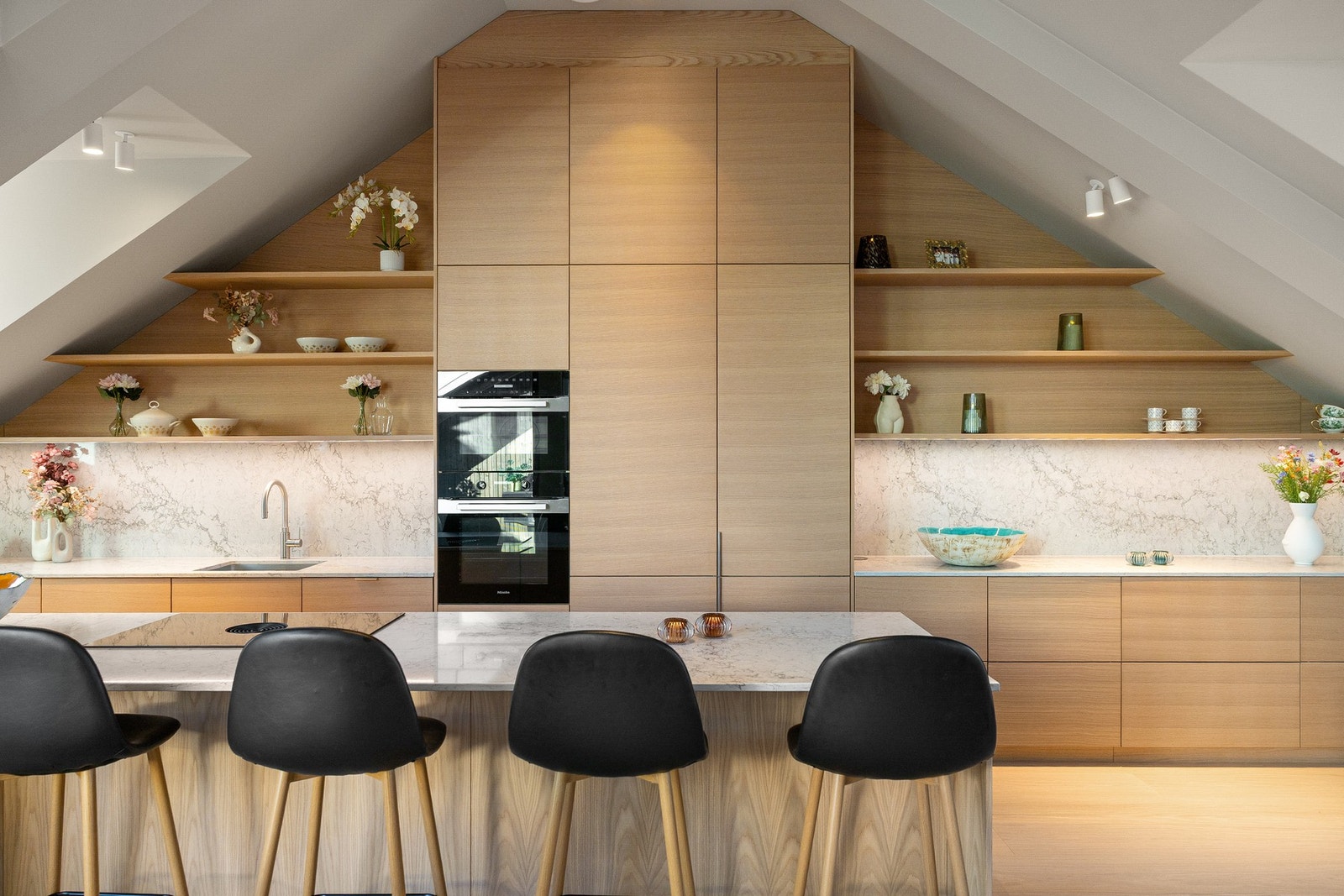 Kjøkkenet har et nordisk uttrykk med glatte fronter i eikestruktur. Kjøkkenøya gir rom for fire sitteplasser, og spisegruppen er plassert i sonen mellom stue og kjøkken. Galleribilde