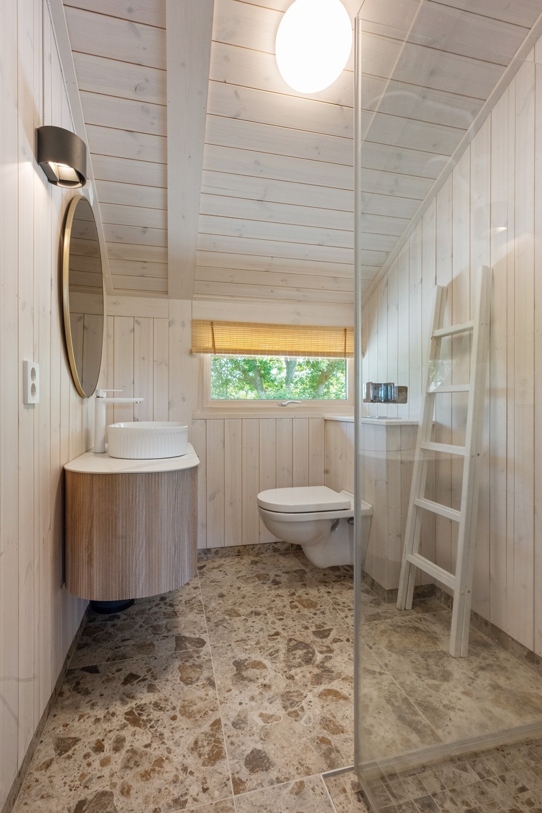 Badet er innredet i lyse toner og har dusj, servant og toalett. Galleribilde