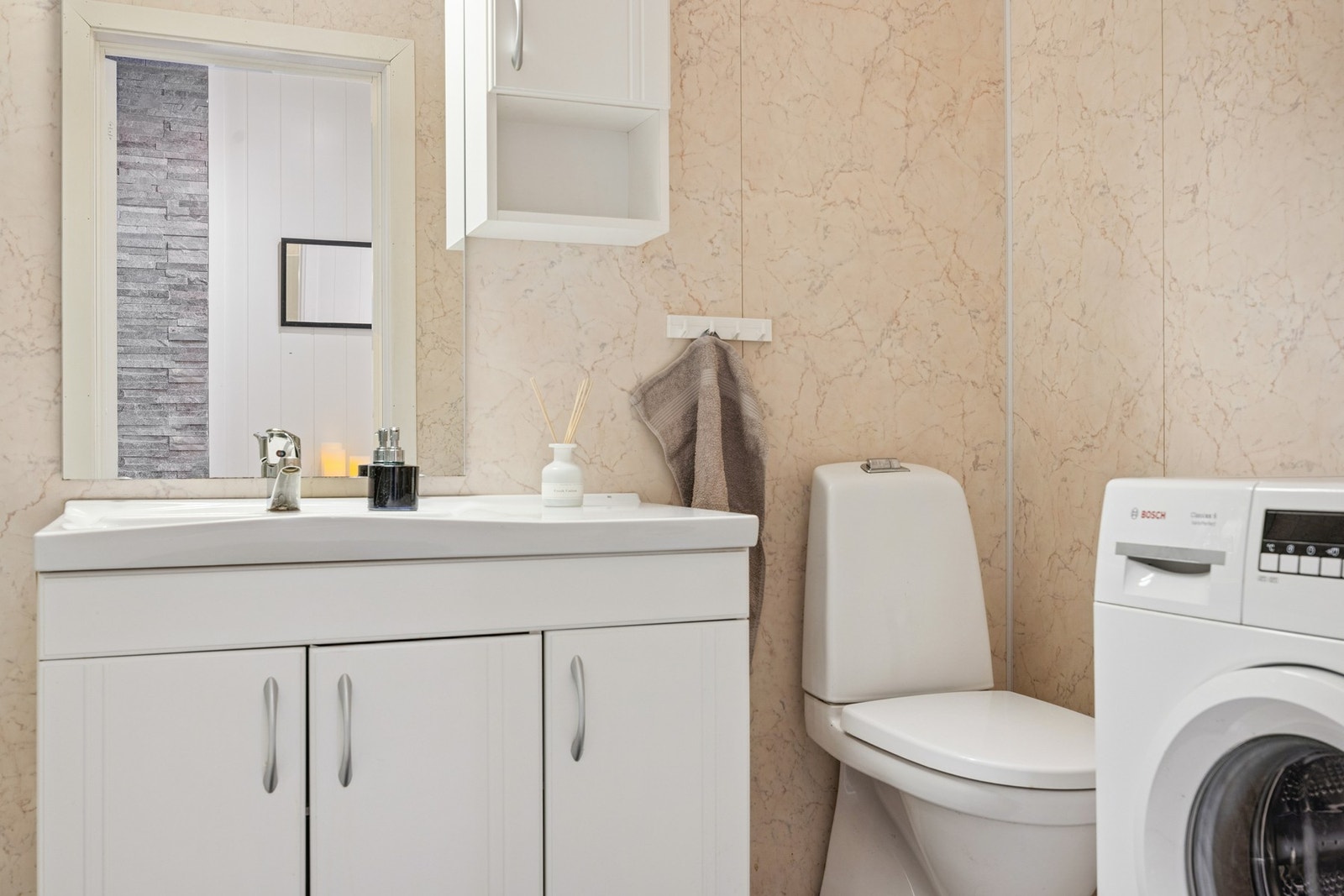 Badet er utstyrt med toalett, servant i innredning, dusjkabinett og opplegg for vaskemaskin. Galleribilde