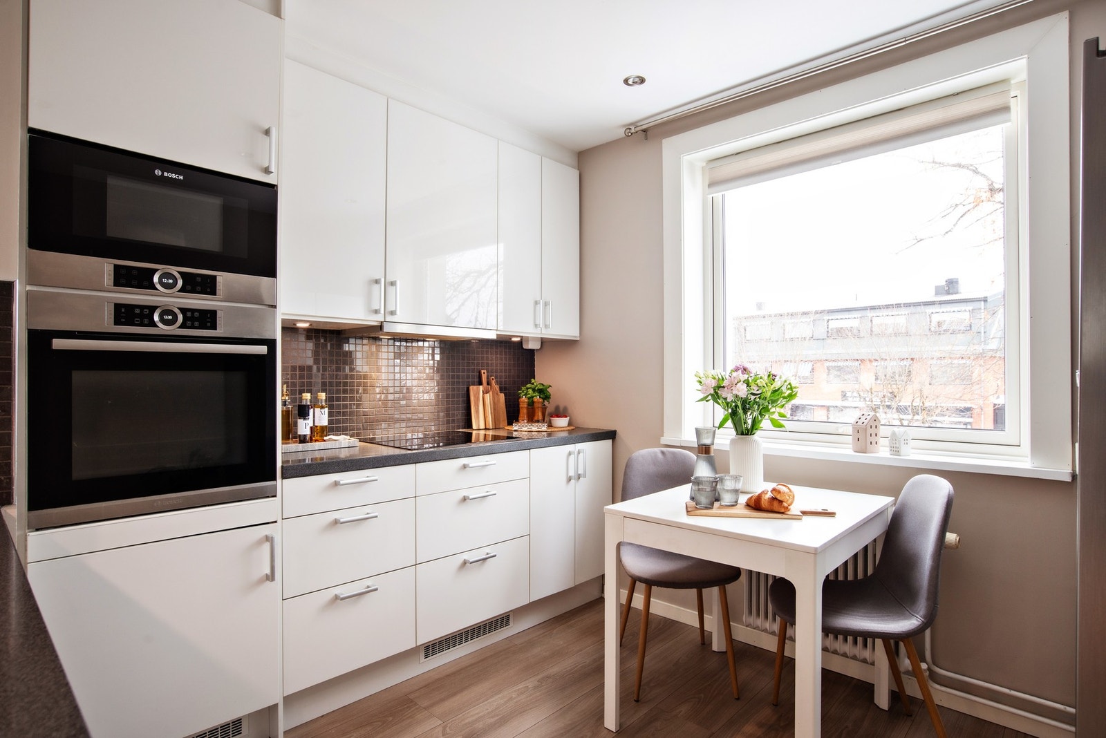 Pen og stilsikker Epoq-kjøkken fra 2017 med benkeplate i stein og ellers glatte fronter. Galleribilde