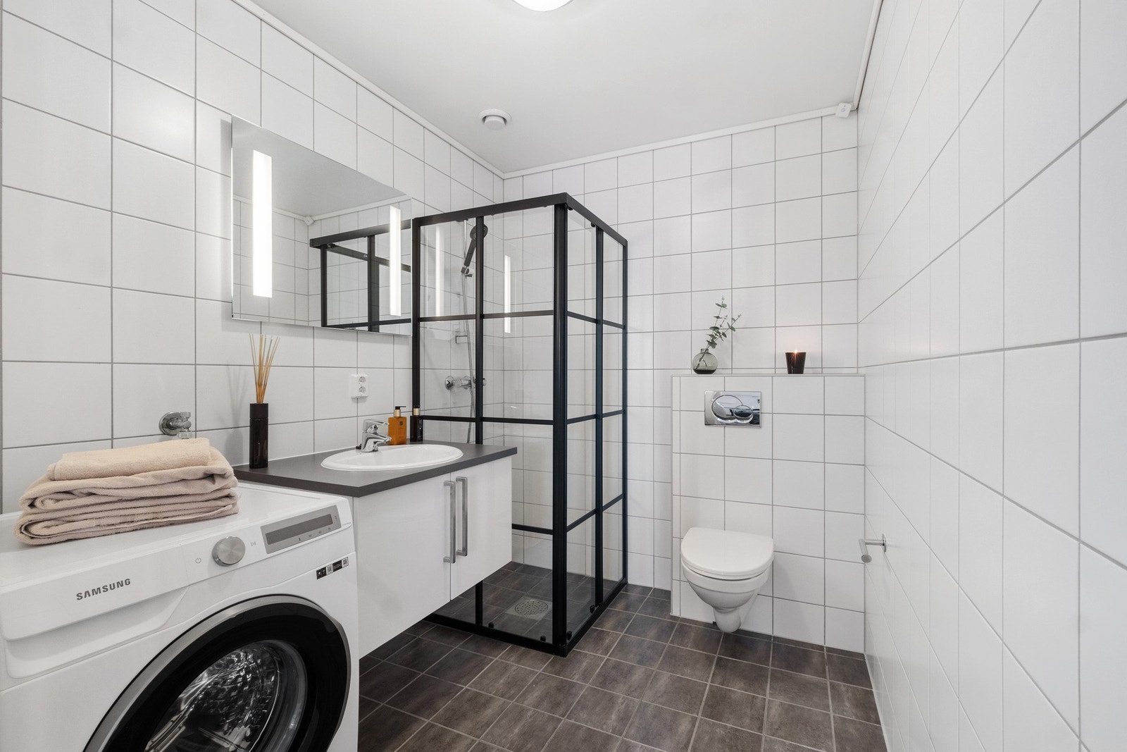 Flislagt bad/vaskerom med dusjnisje, vegghengt WC og servantseksjon. Opplegg for vaskemaskin og varmekabler i gulv. Galleribilde