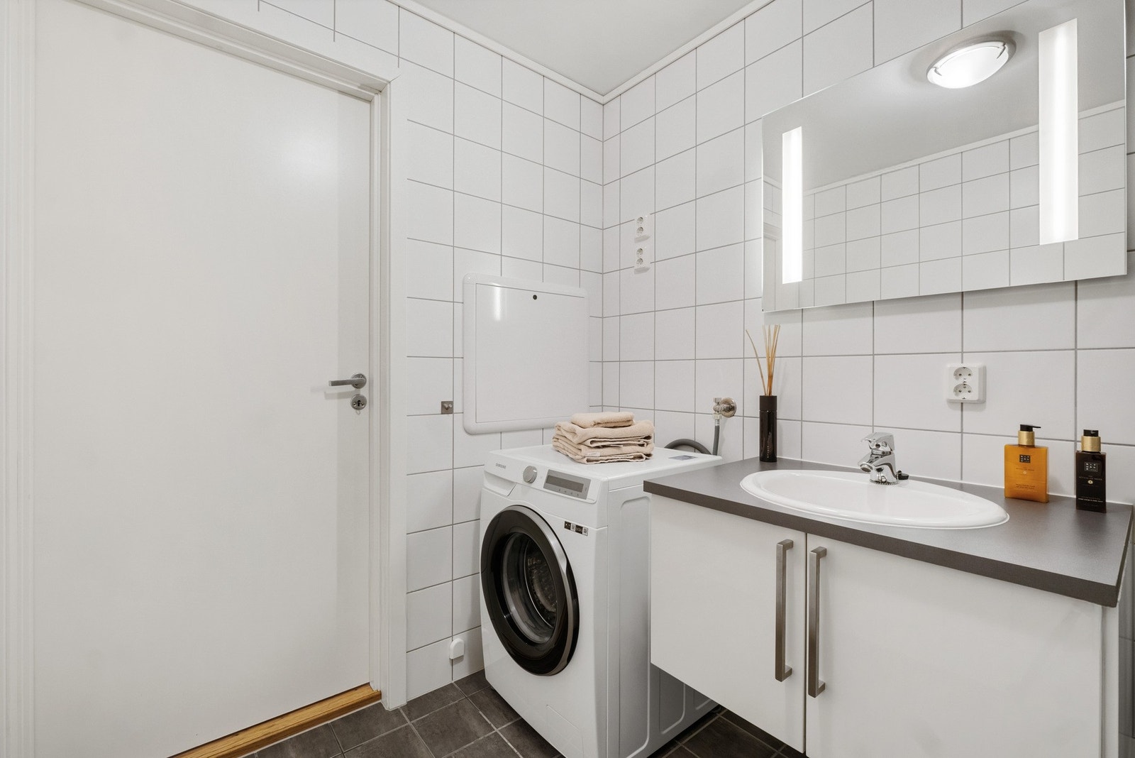 Flislagt bad/vaskerom med dusjnisje, vegghengt WC og servantseksjon. Opplegg for vaskemaskin og varmekabler i gulv. Galleribilde