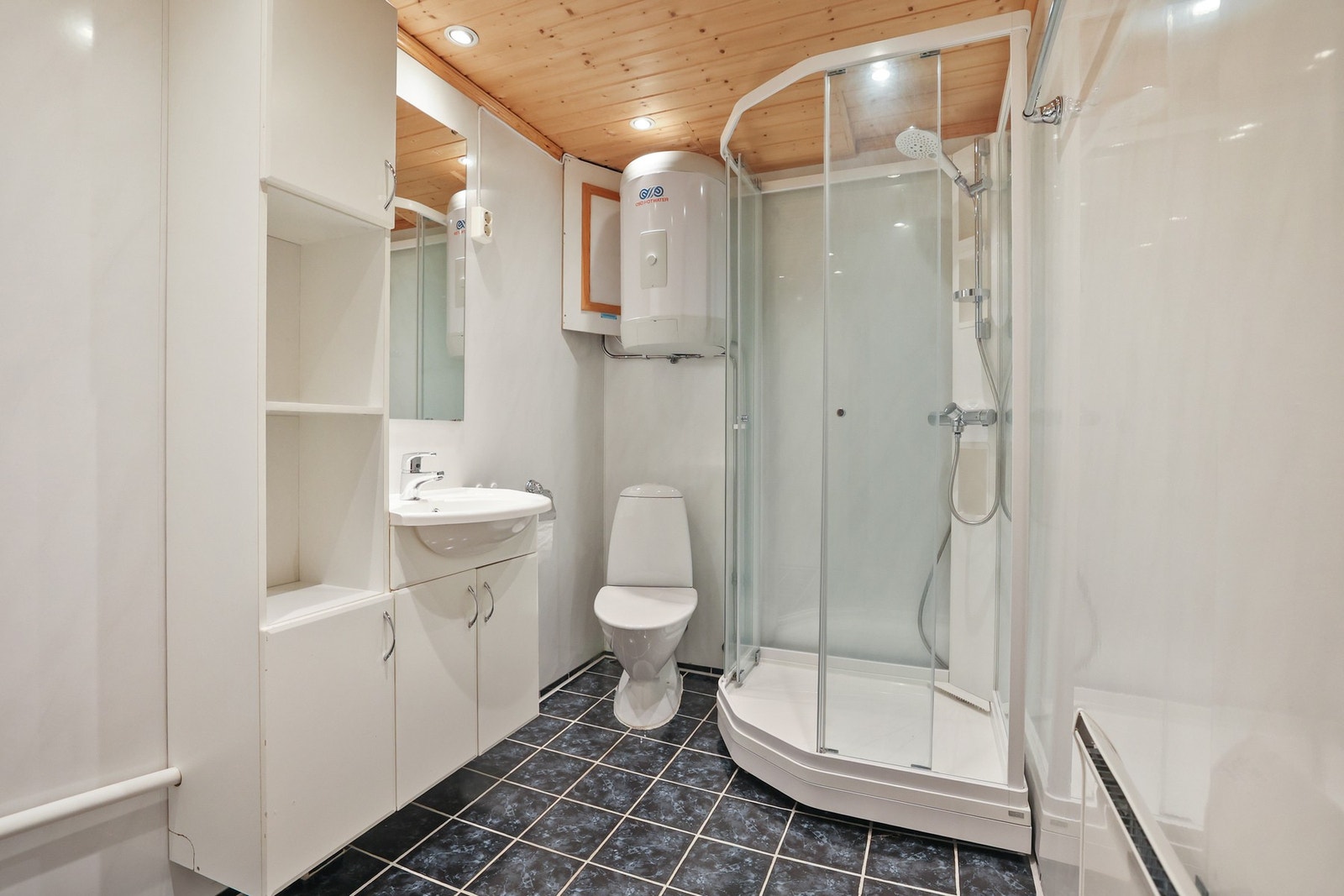 Badet er praktisk utformet med flislagt gulv og baderomsplater på veggene. Galleribilde