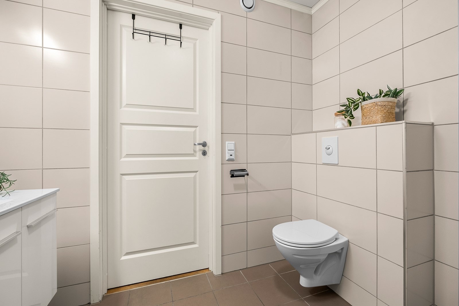 Badet er innredet med dusjkabinett, veggmontert toalett, innredning med servant og opplegg for vaskemaskin (Kran og avløp). Galleribilde