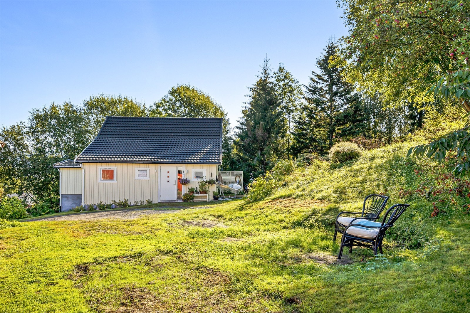 Parkering på egen gruset gårdsplass med lader for el-bil (2021) på husveggen Galleribilde