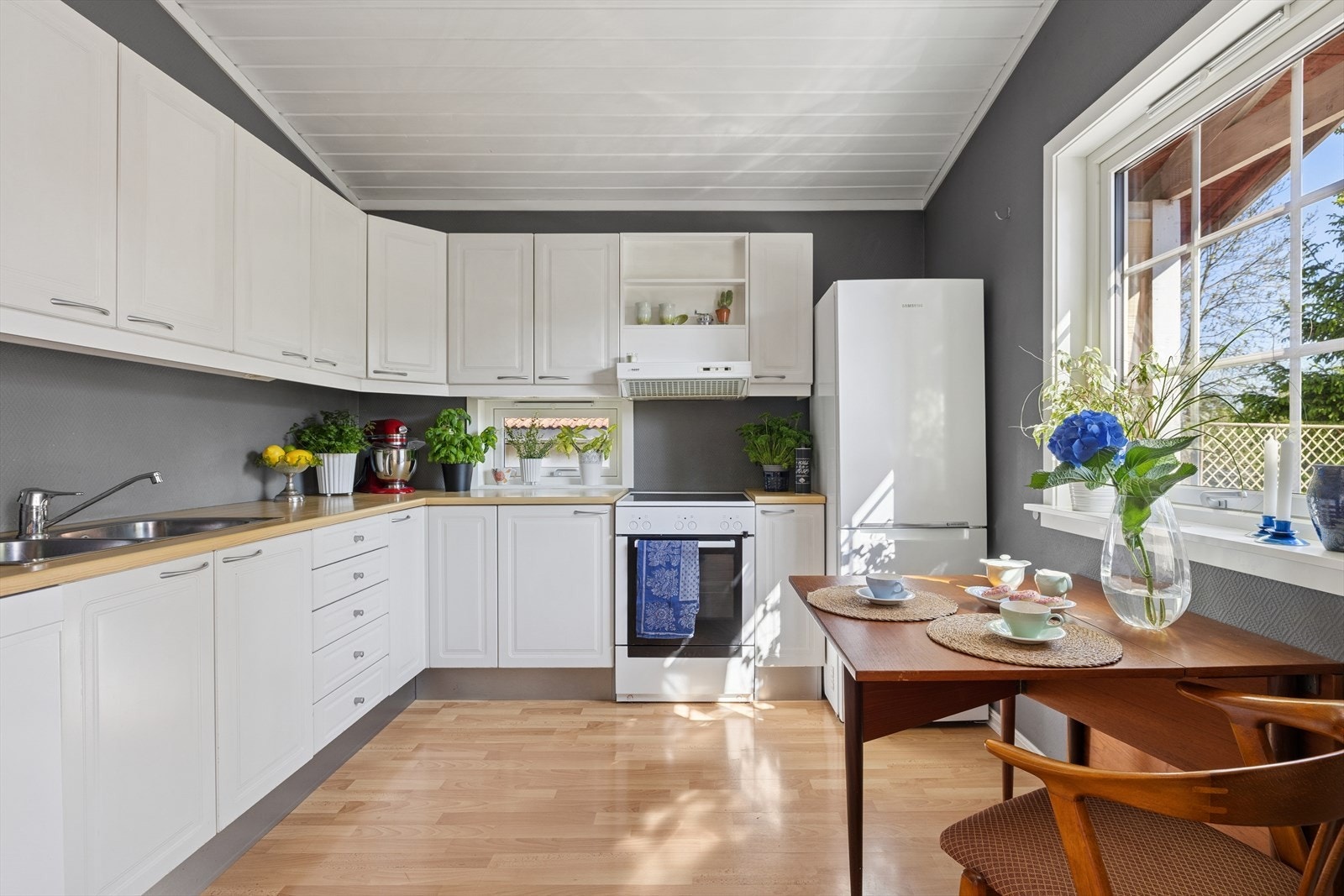 Pent kjøkken med rom for egen spiseplass ved kjøkkenvinduet. Galleribilde