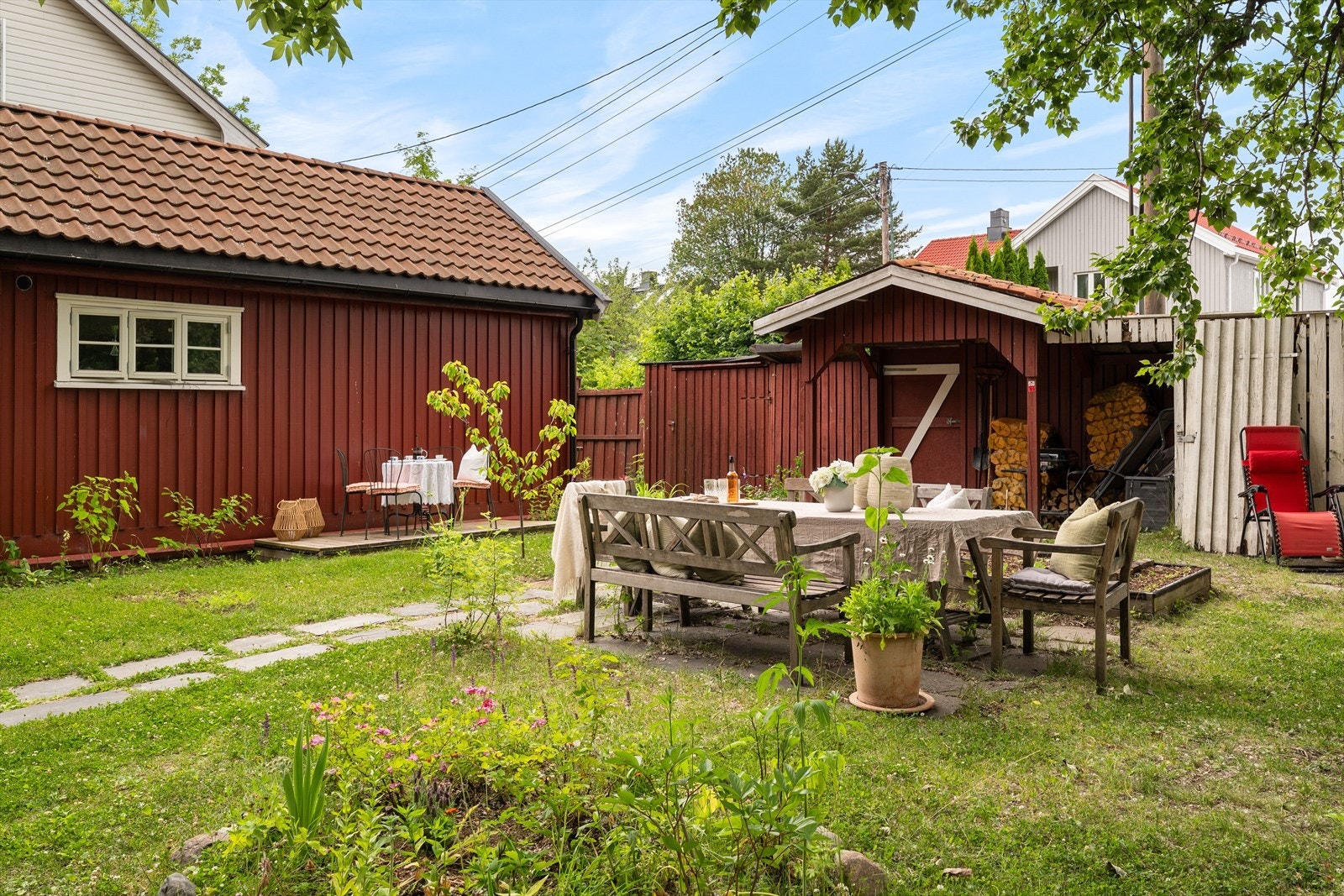 Idyllisk hage som er pent opparbeidet med gressplen, diverse beplantning, hellebelagte gangveier og fine sitteplasser. Galleribilde