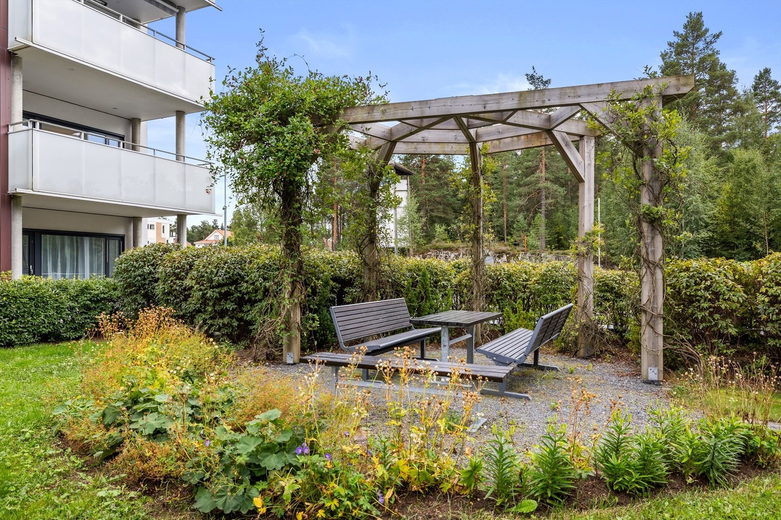 En hyggelig pergola i felleshagen, perfekt for en rolig stund utendørs. Galleribilde